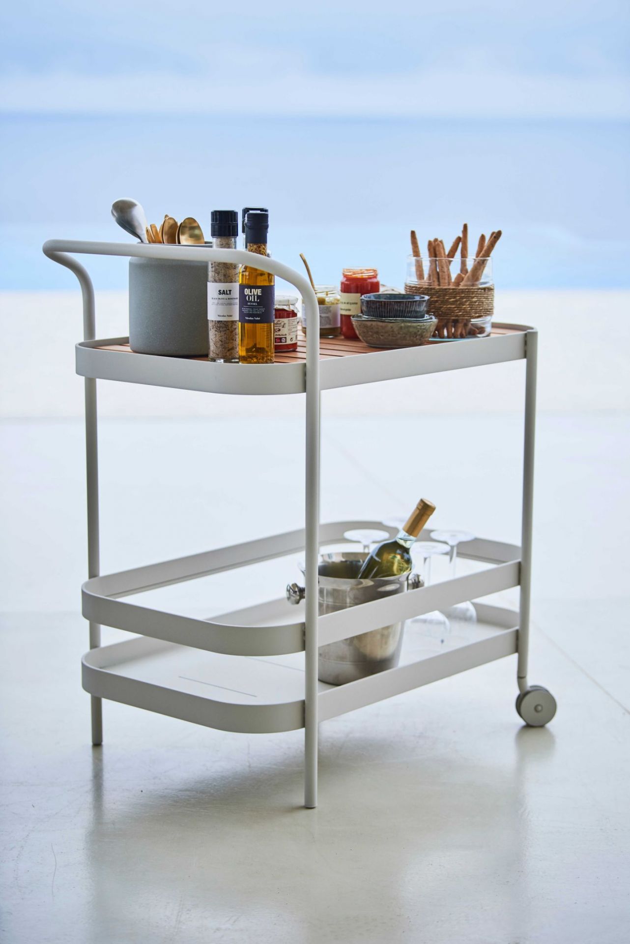 Lavagrauer Cane-Line Rollwagen mit Speisen und Getränken. Moderner Servierwagen für den Innen- und Außenbereich.