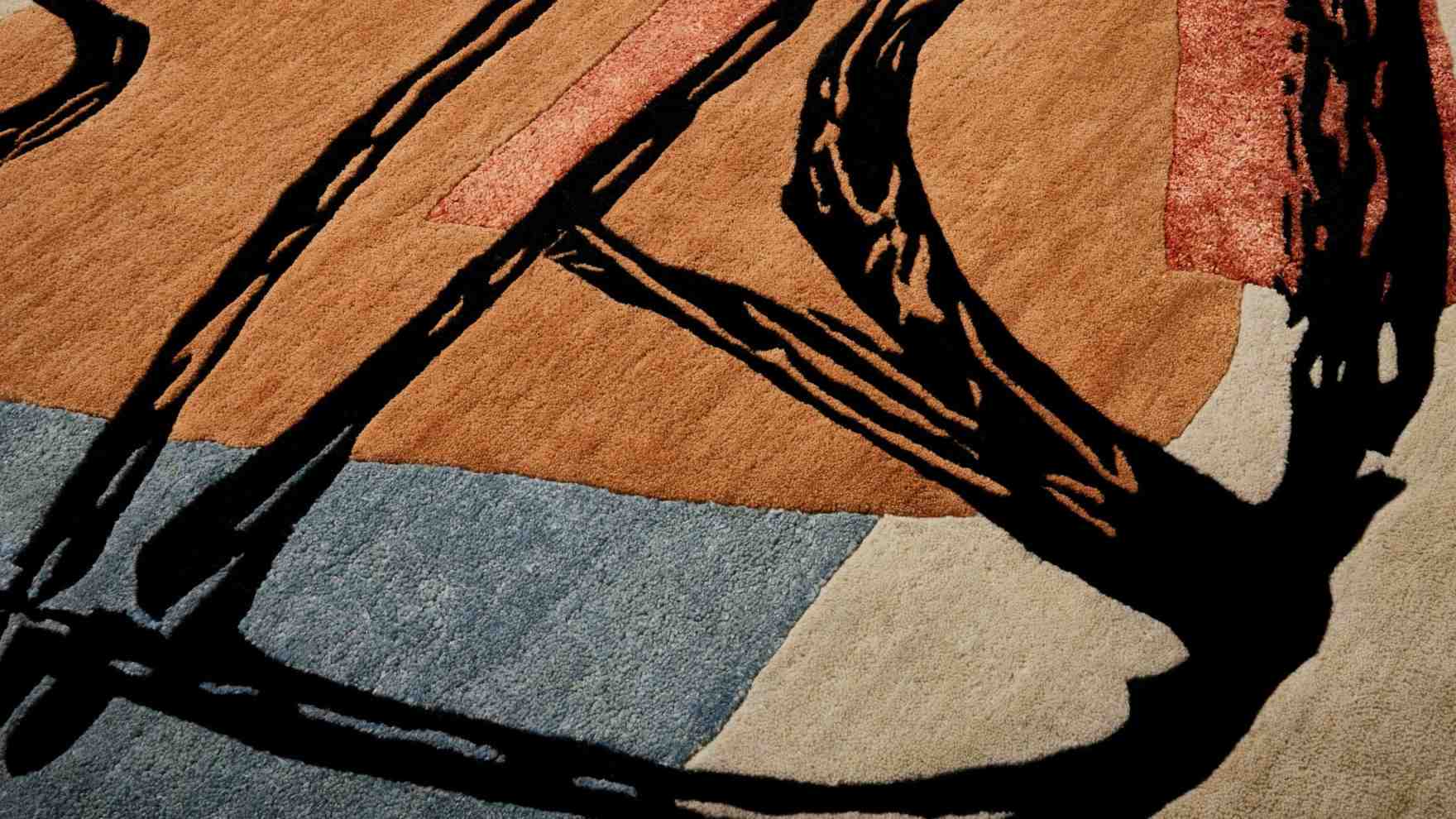 Detailaufnahme des Cassina Teppichs La Main Ouverte mit abstraktem Muster in Braun-, Beige- und Blautönen.