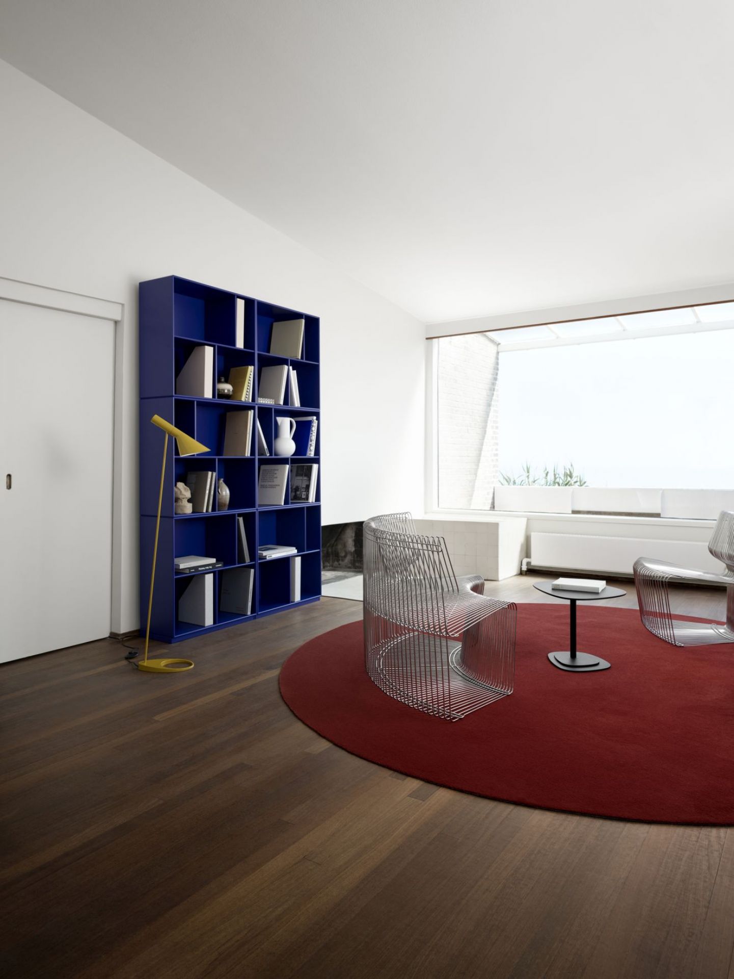 Blaues READ Bücherregal von Monarch Montana im modernen Wohnzimmer mit Büchern und Deko.