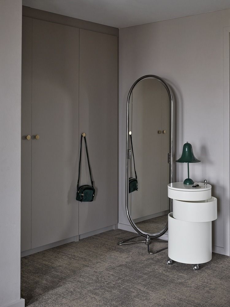 Grüne Pantop Tischleuchte von Verpan auf weißem Nachttisch neben einem Spiegel und Kleiderschrank.