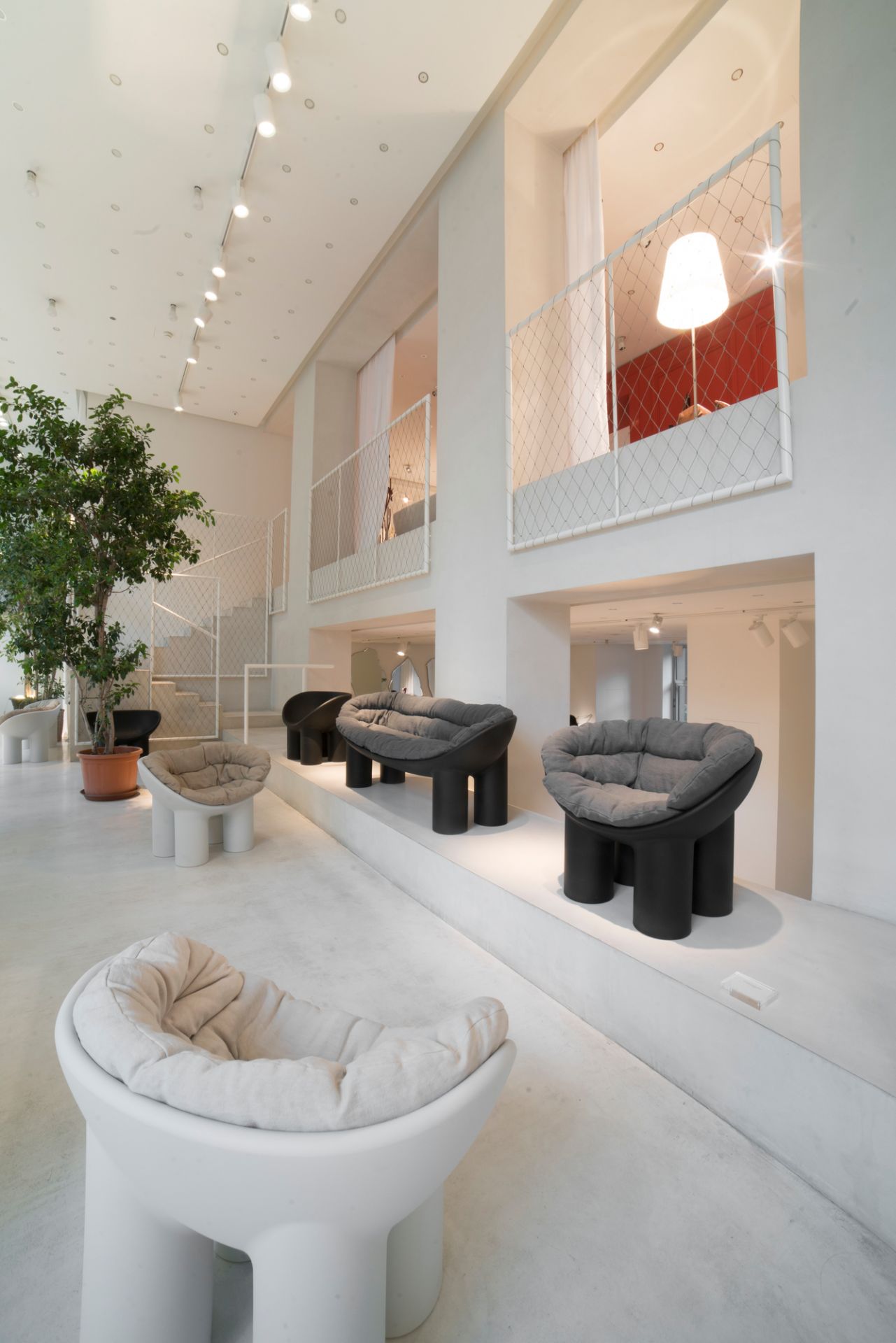 Innenansicht mit Roly Poly Bank Driade Charcoal und weiteren Sitzmöbeln in minimalistischem Design.