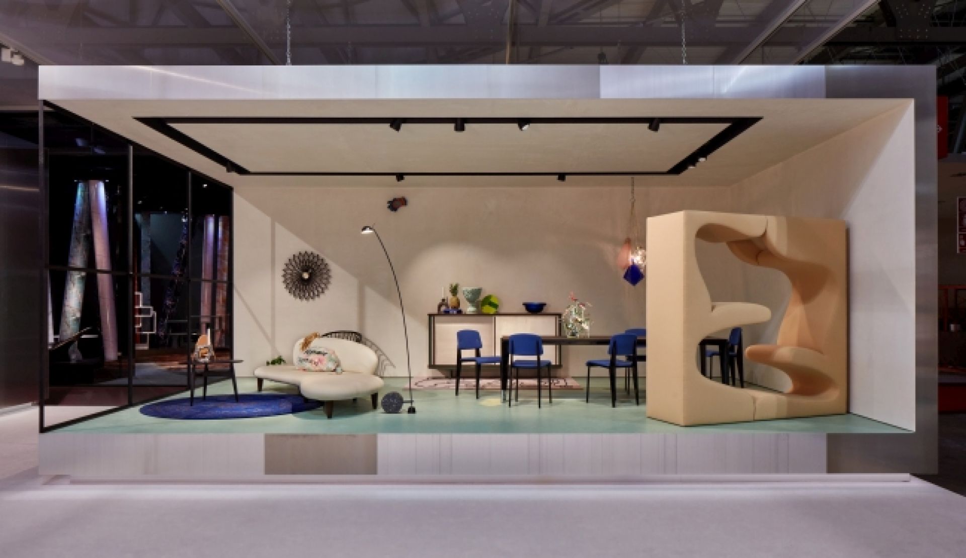 Ausstellungsraum mit Vitra Freeform Sofa, Esstisch und skulpturalem Sessel in Beige und Blau.