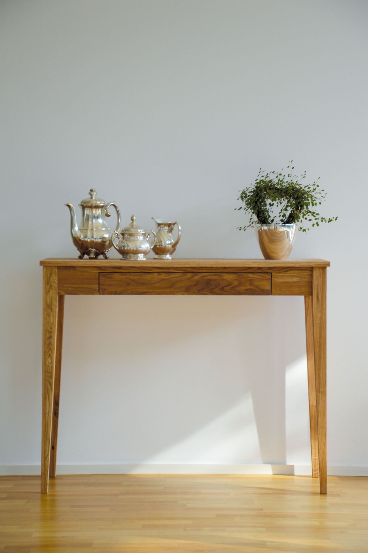 Bonny Beistelltisch von Jan Kurtz aus Holz mit Schublade, Teekanne und Pflanze.