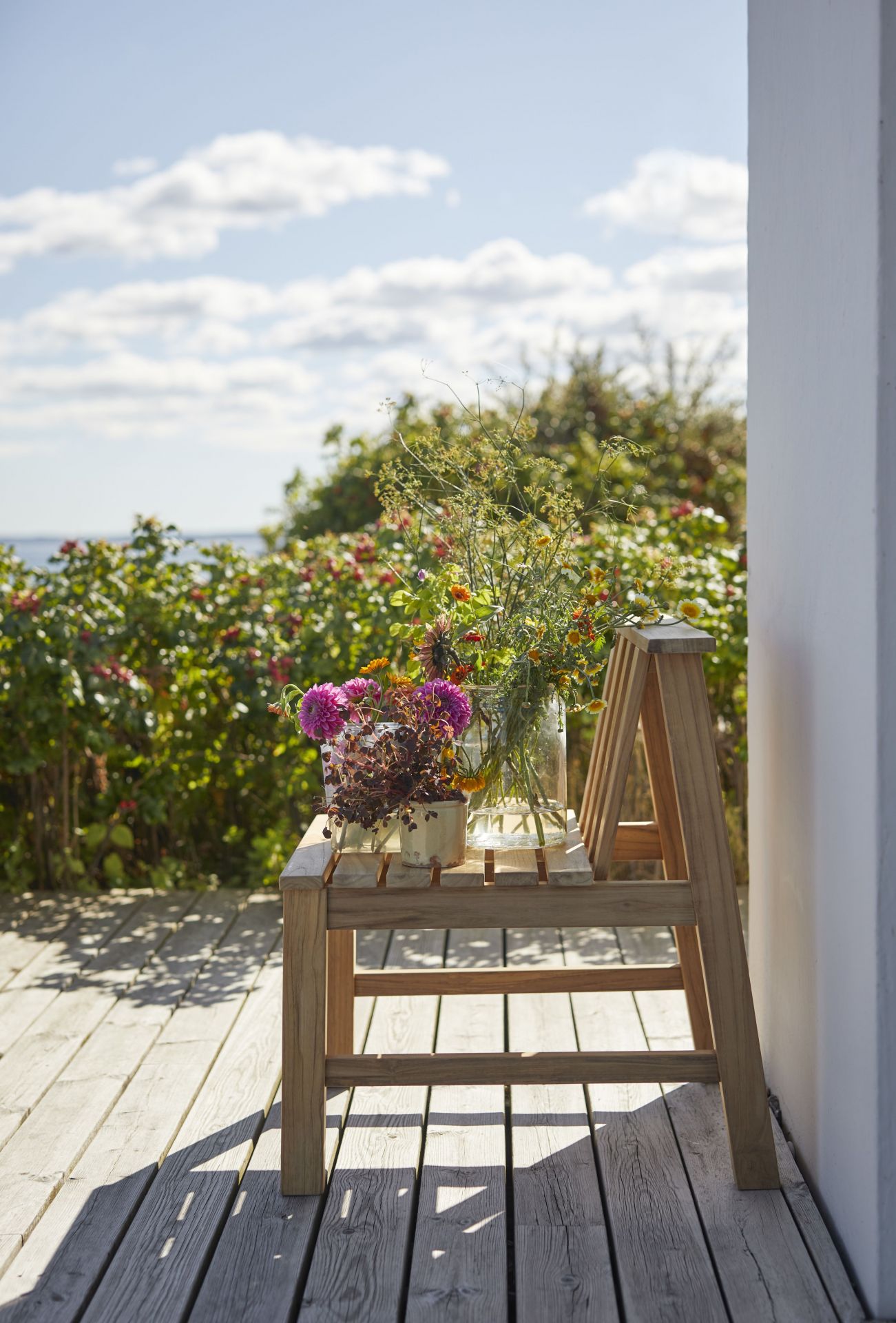 Cadence Stuhl aus Teakholz von Skagerak mit Blumen auf einer Terrasse im Freien.