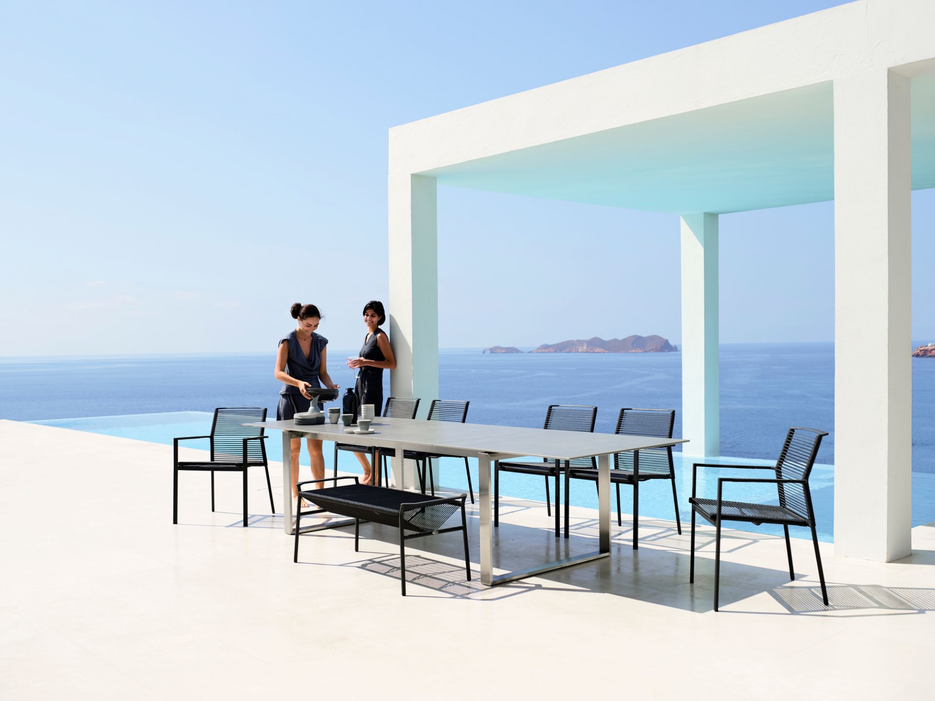 Cane-Line Edge Outdoor Sessel, stapelbar, in Schwarz am Pool mit Meerblick. Gartenmöbel.