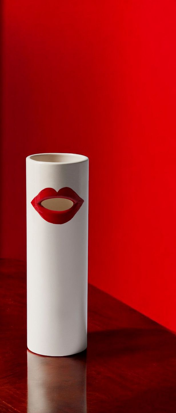 Weiße Cassina Vase "Bocca" mit roten Lippen auf rotem Hintergrund, moderne Designervase.