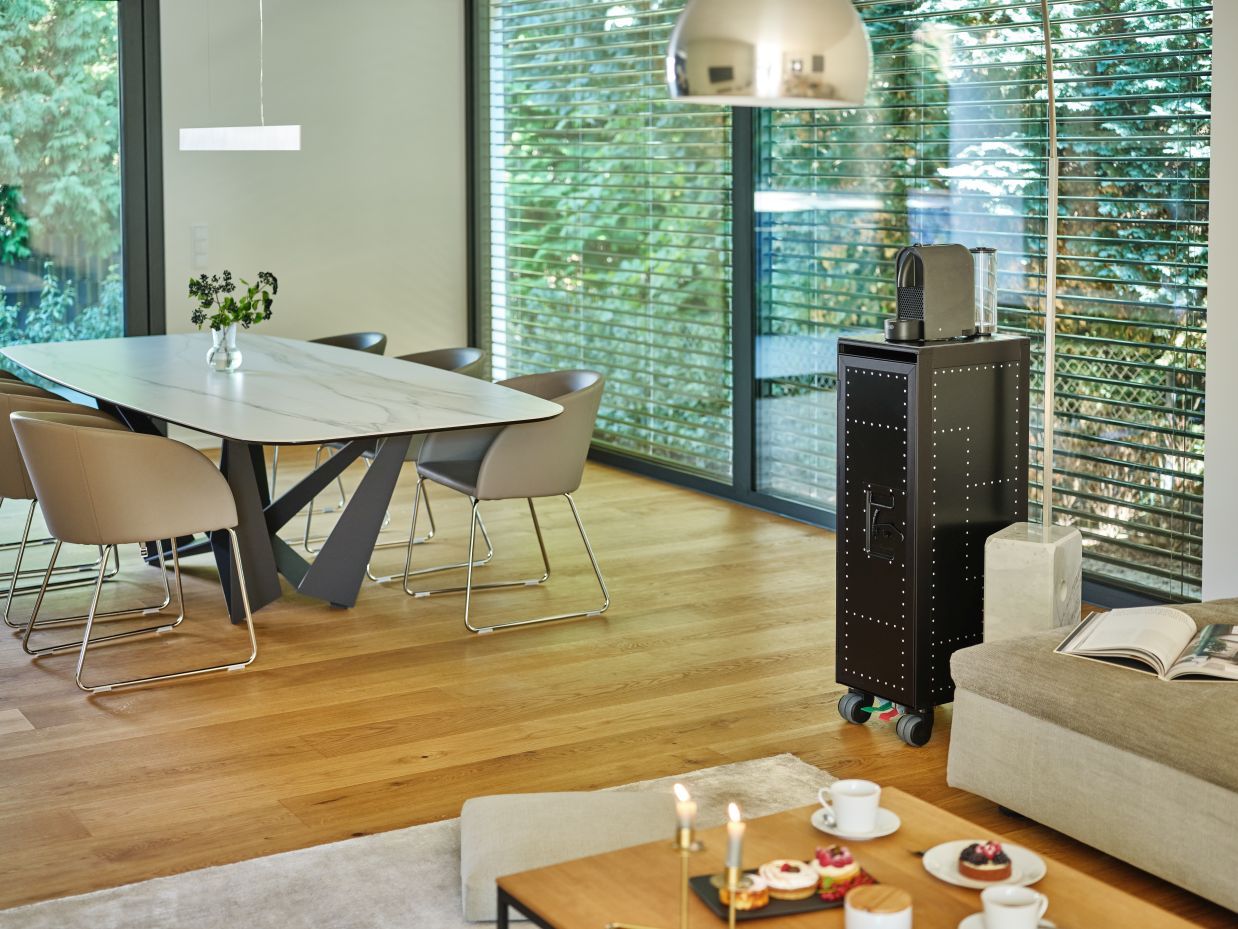 Schwarzer Rivet Rocker Flugzeugtrolley mit transparenter Tür als stylische Bordbar im modernen Wohnzimmer.