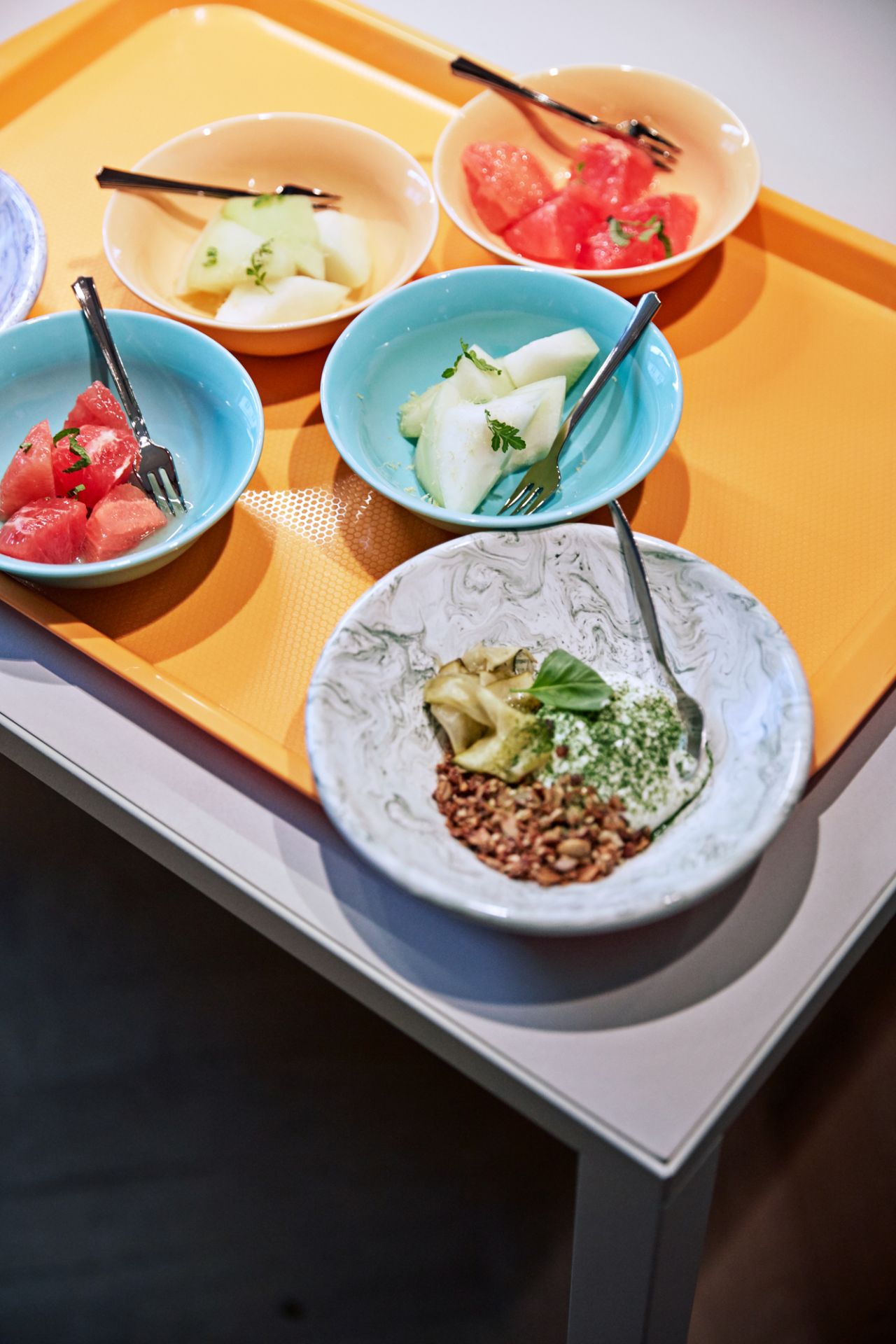 Nahaufnahme von verschiedenen gefüllten, farbigen Soft Ice Tellern von Hay auf einem orangefarbenen Tablett.