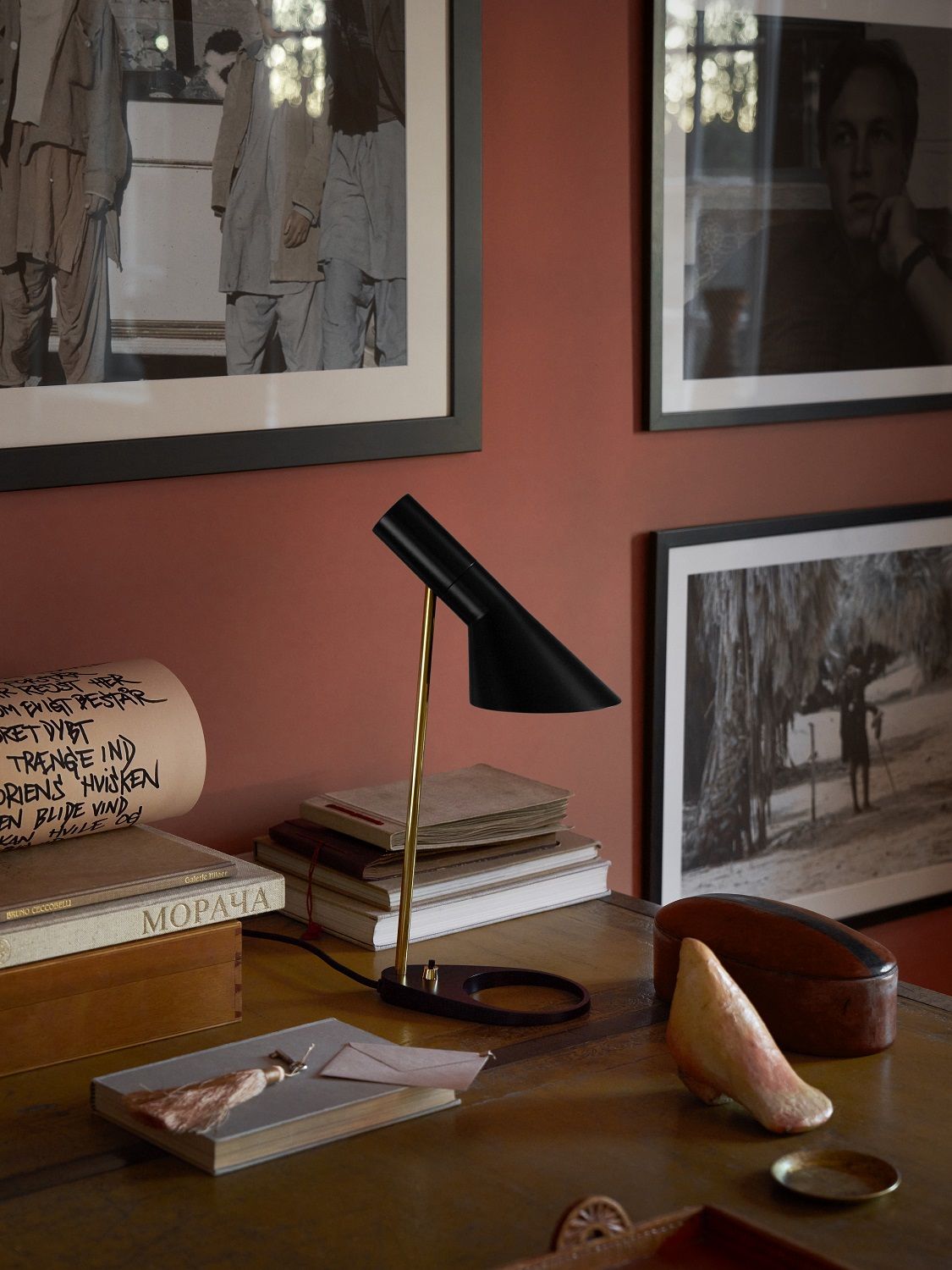 AJ Mini Tischleuchte von Louis Poulsen, schwarzes Design, goldener Ständer, auf Schreibtisch mit Büchern.