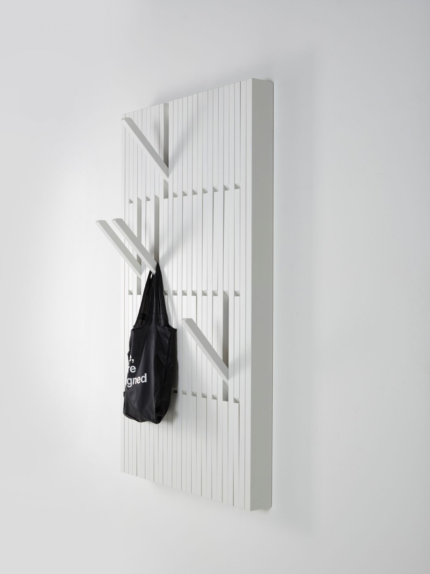 Weiße Piano Wandgarderobe mit Haken und schwarzer Tasche, moderne Garderobenlösung für Flur und Eingangsbereich.