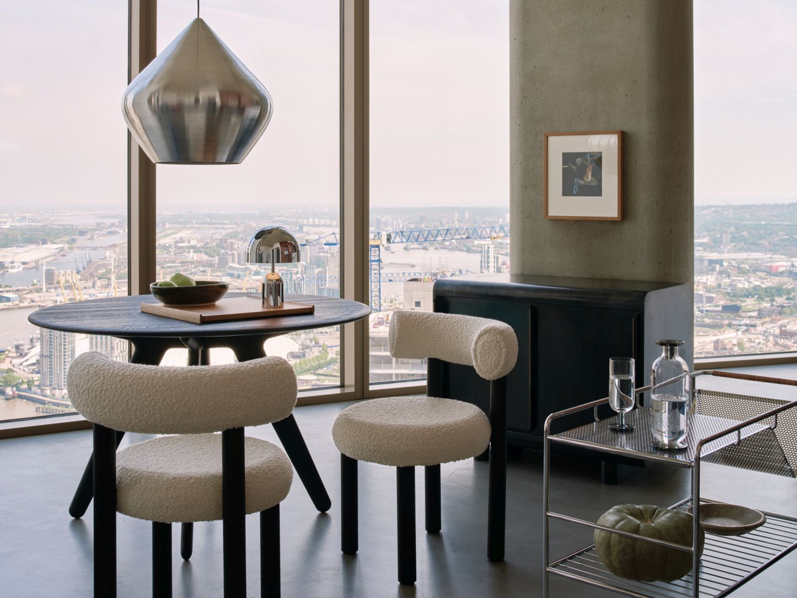 Moderne Inneneinrichtung mit Tom Dixon Unbeaten Stout Pendelleuchte über Esstisch und Stühlen vor Fenster mit Stadtblick.