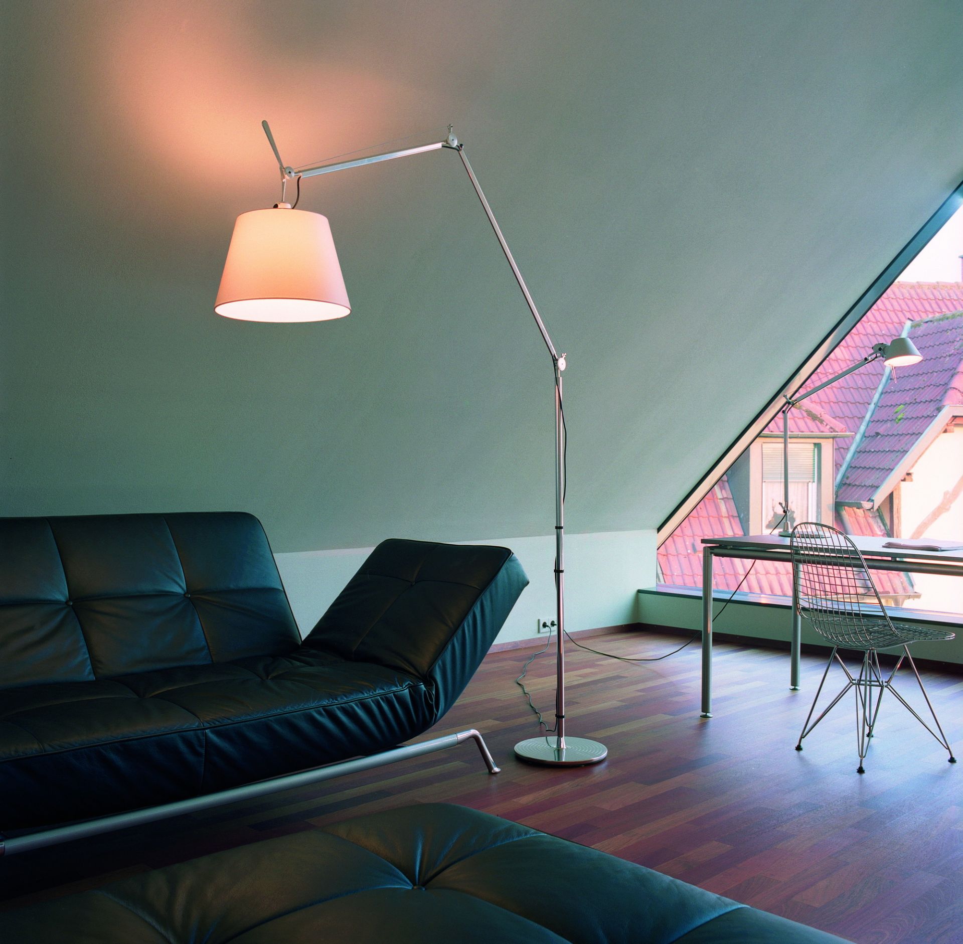 Artemide Tolomeo Mega LED Stehleuchte mit Standfuß und Stab neben schwarzer Ledercouch im Wohnzimmer.