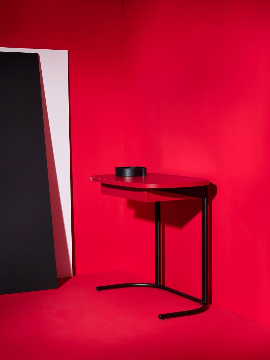 Roter Schönbuch Tori Sekretär Schreibtisch mit schwarzem Stifthalter und minimalistischem Design vor rotem Hintergrund.