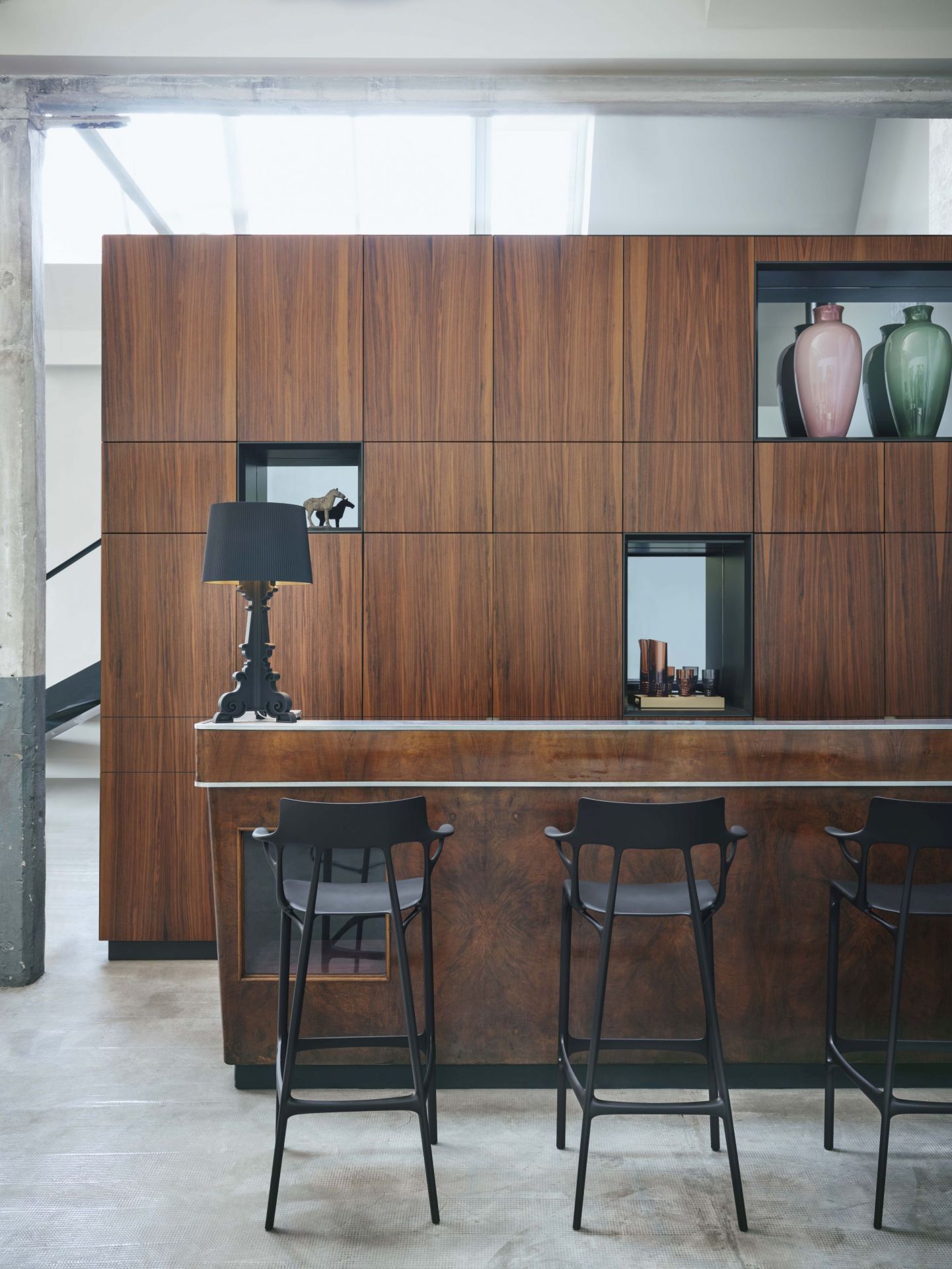 Bourgie Tischleuchte von Kartell in Schwarz auf einer Bar mit Hockern. Designleuchte.