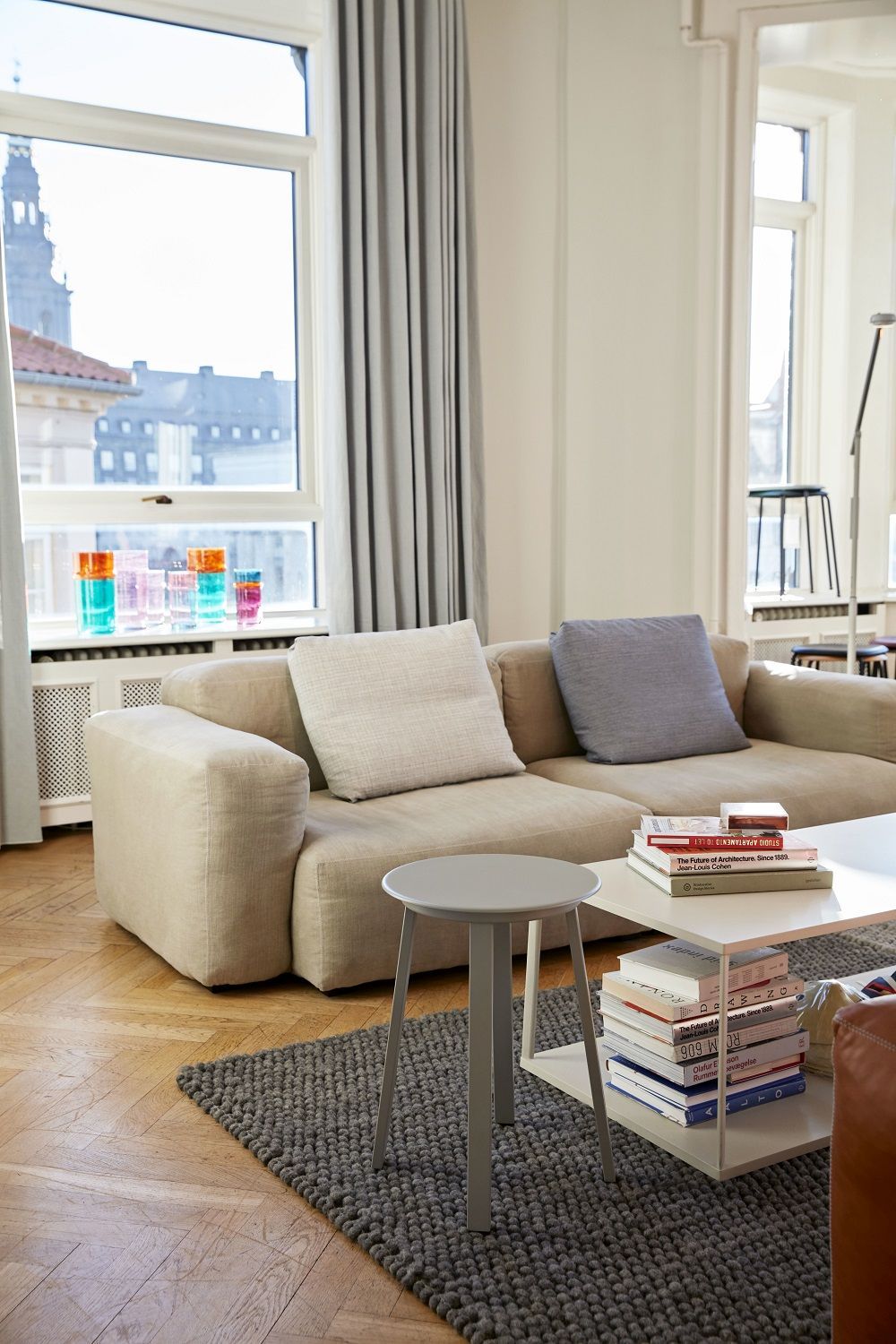 Grauer Revolver Stool Hocker von Hay im modernen Wohnzimmer auf einem Teppich.