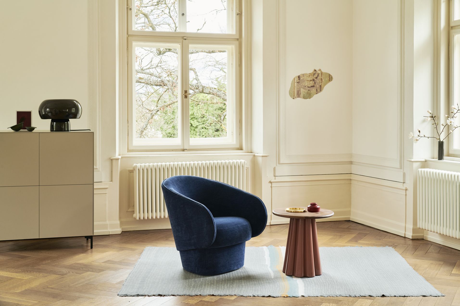 Fonte Tischleuchte GRAPHITE GREY auf Kommode in stilvollem Wohnraum mit Sessel und Beistelltisch.