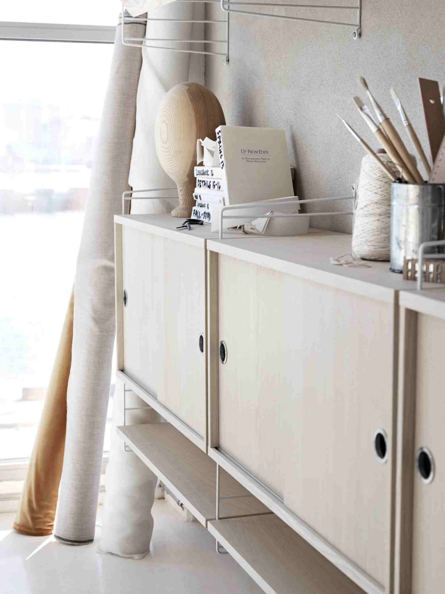 String Regalsystem mit Schiebetüren, Holzregalen und weißen Drahtleitern für Wohnzimmer und Büro.