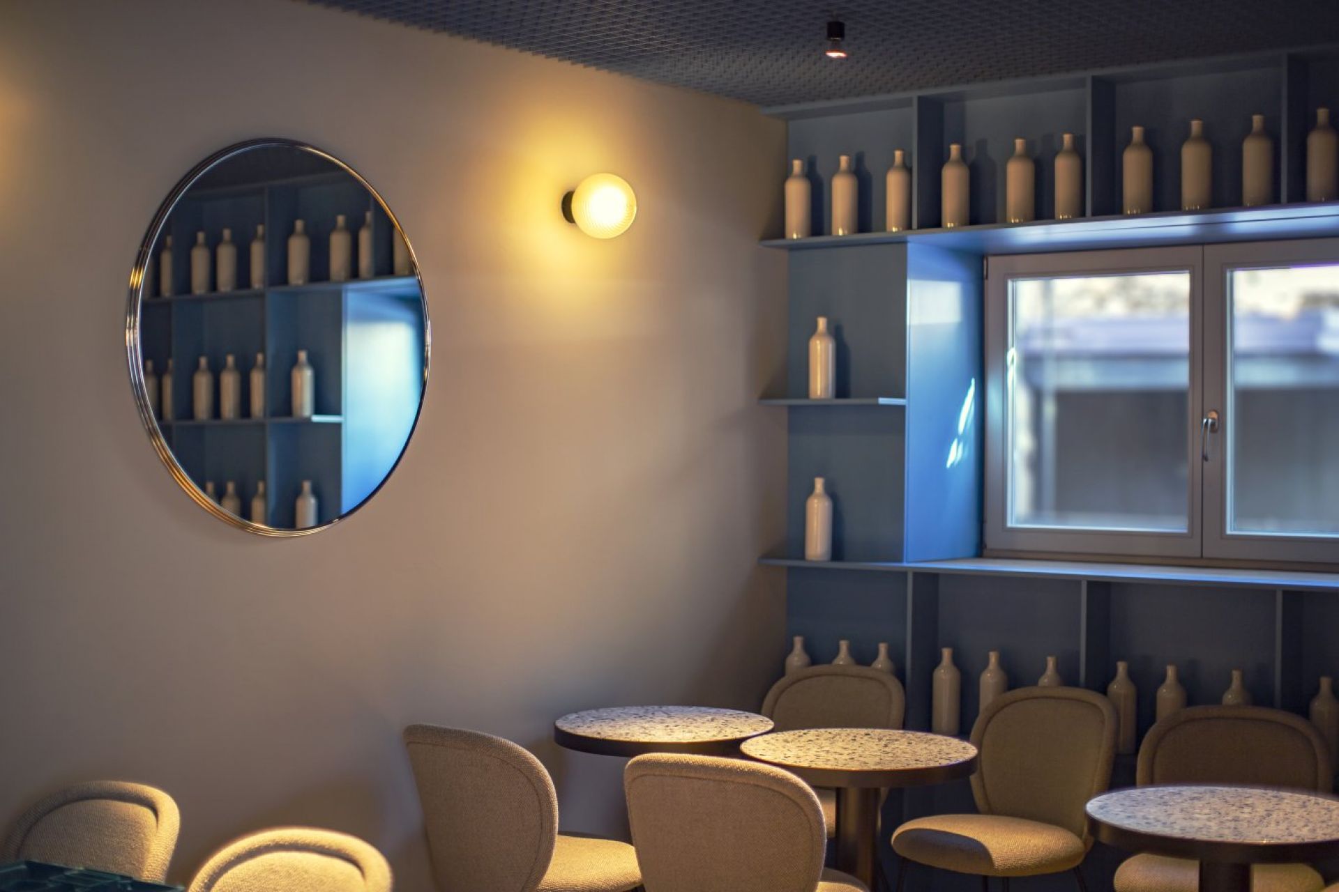 Stimmungsvolles Interieur mit Stellar Wandleuchte von Pulpo, die warmes Licht spendet. Auberginefarbene Wand.