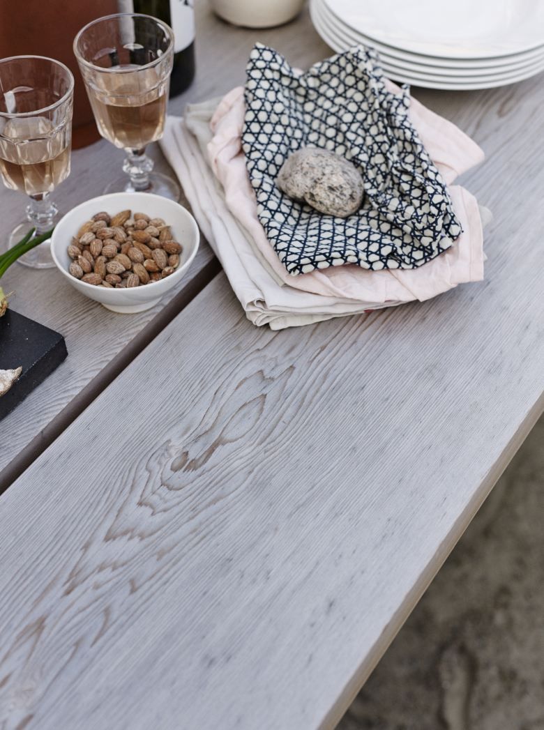 Detailaufnahme des Overlap Table Outdoor von Skagerak: Gartentisch mit Speisen und Getränken.