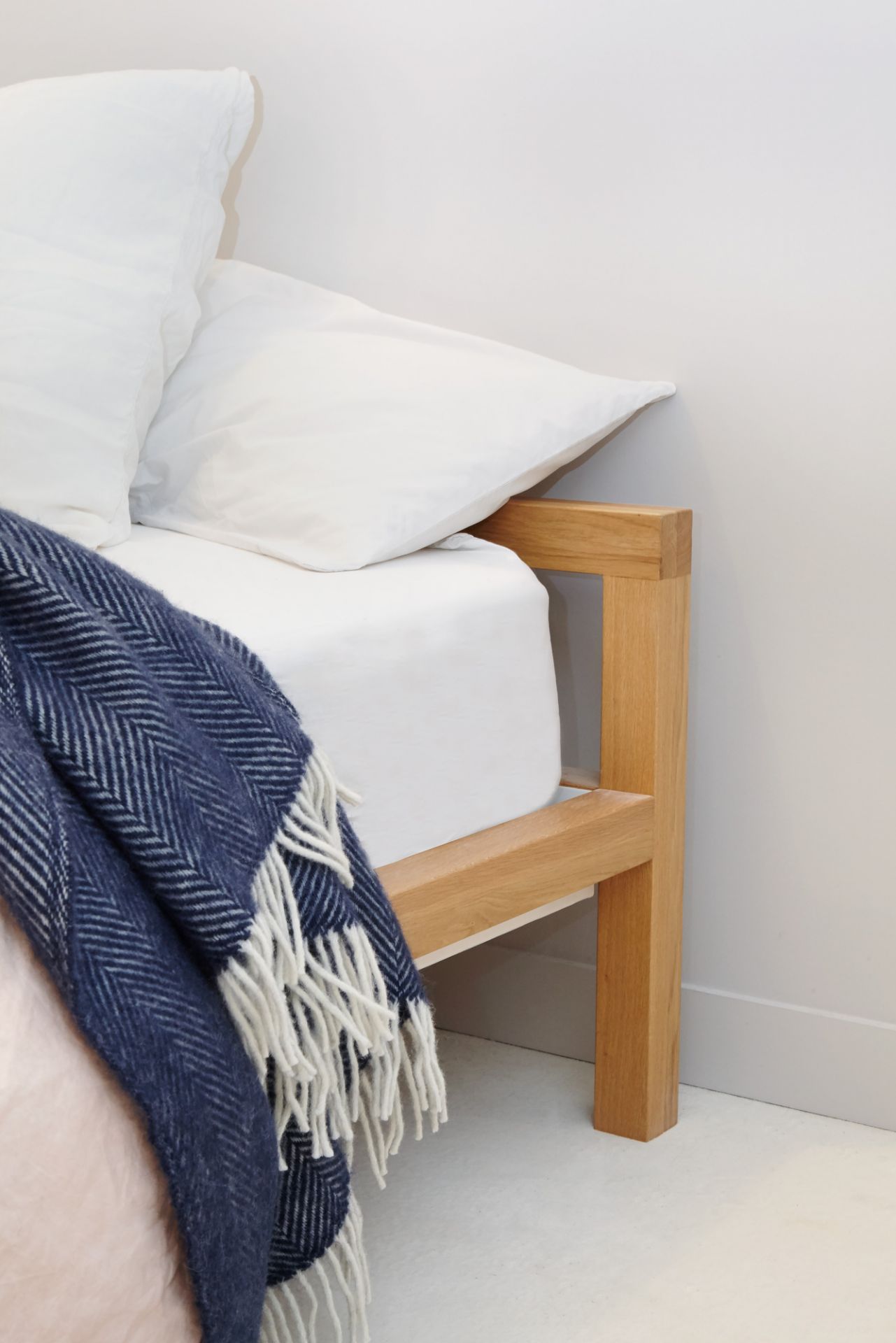 Hans Hansen Pure Bett aus Eiche, 180x200 cm, mit blauer Decke und weißen Kissen.