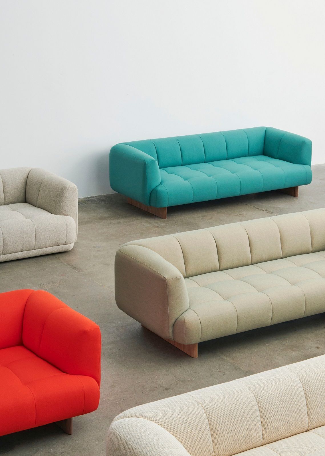Verschiedene Quilton Sofas, darunter ein türkises 2-Sitzer Sofa von Hay, auf einem grauen Boden.