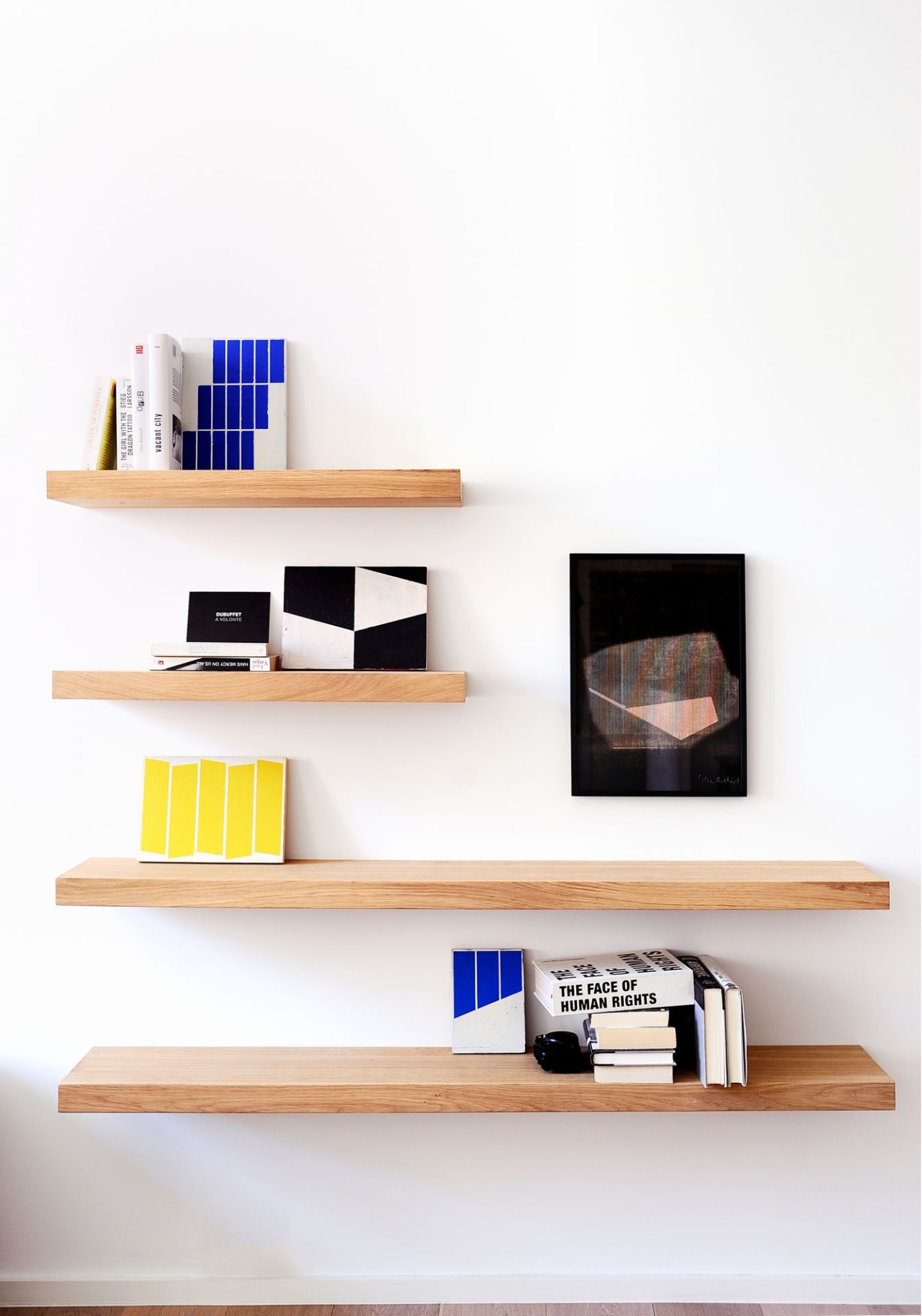 Ethnicraft Wandregal aus Eiche, vier Regalböden an weißer Wand mit Deko-Objekten und Büchern.