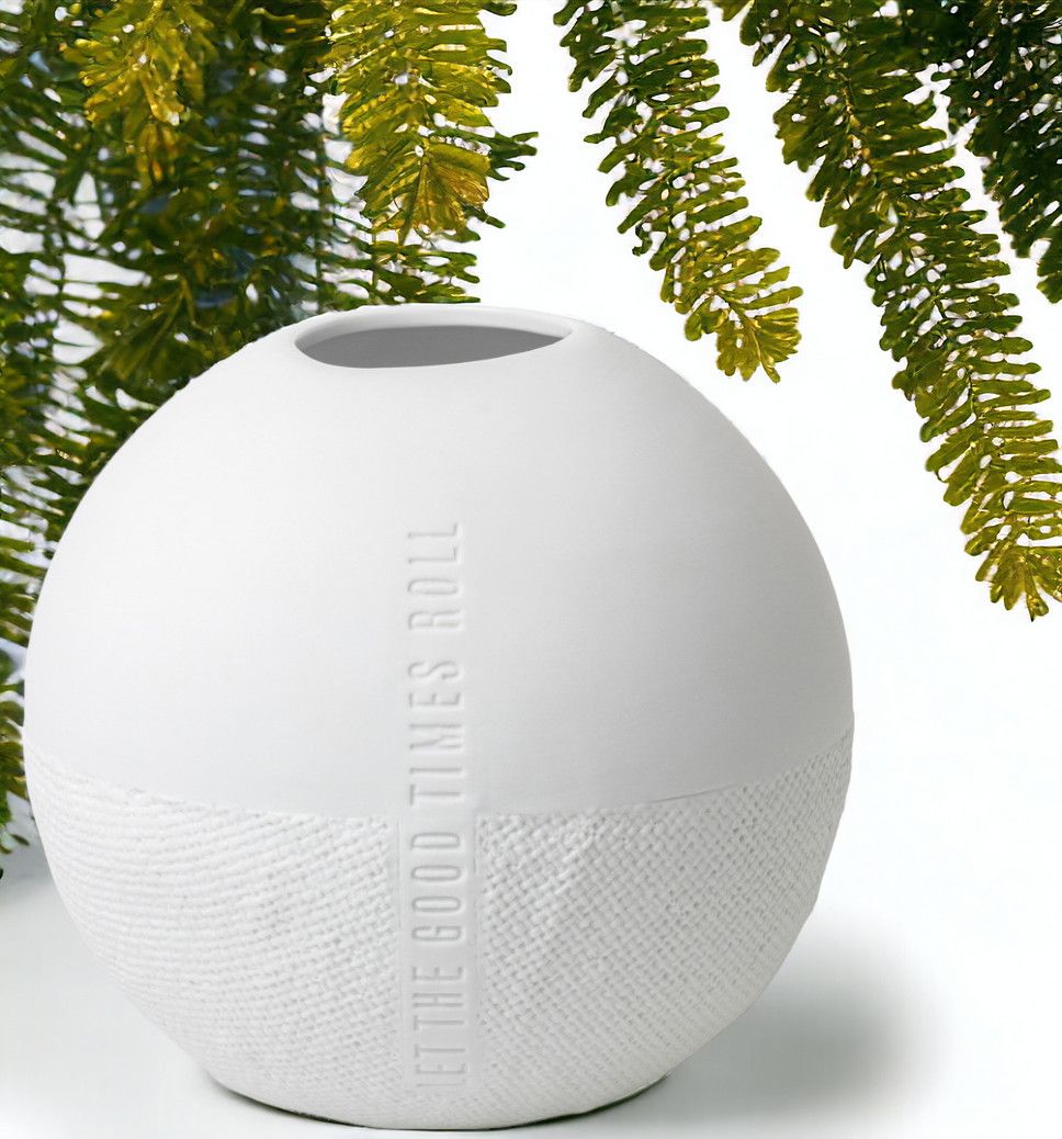 Weiße, runde Räder Vase "Let the Good Times Roll" mit Textur und Tannenzweig im Hintergrund.