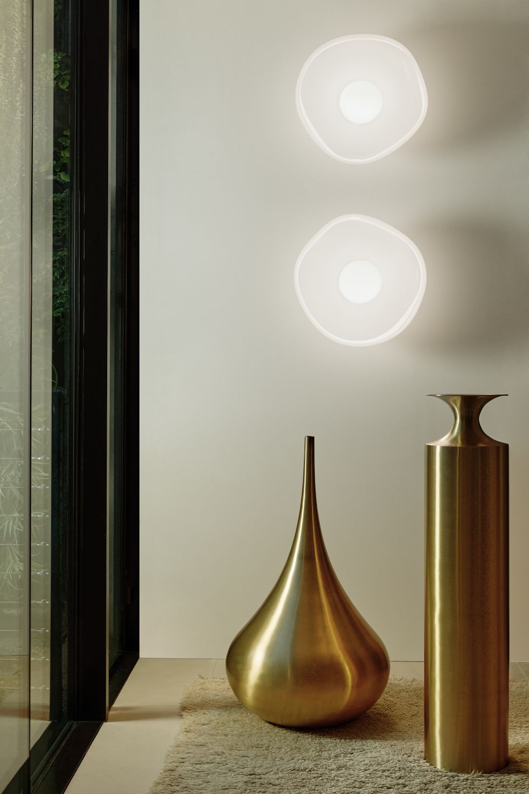 Zwei Tom Dixon Melt Surface LED-Wandleuchten in Opal und Gold an einer Wand.