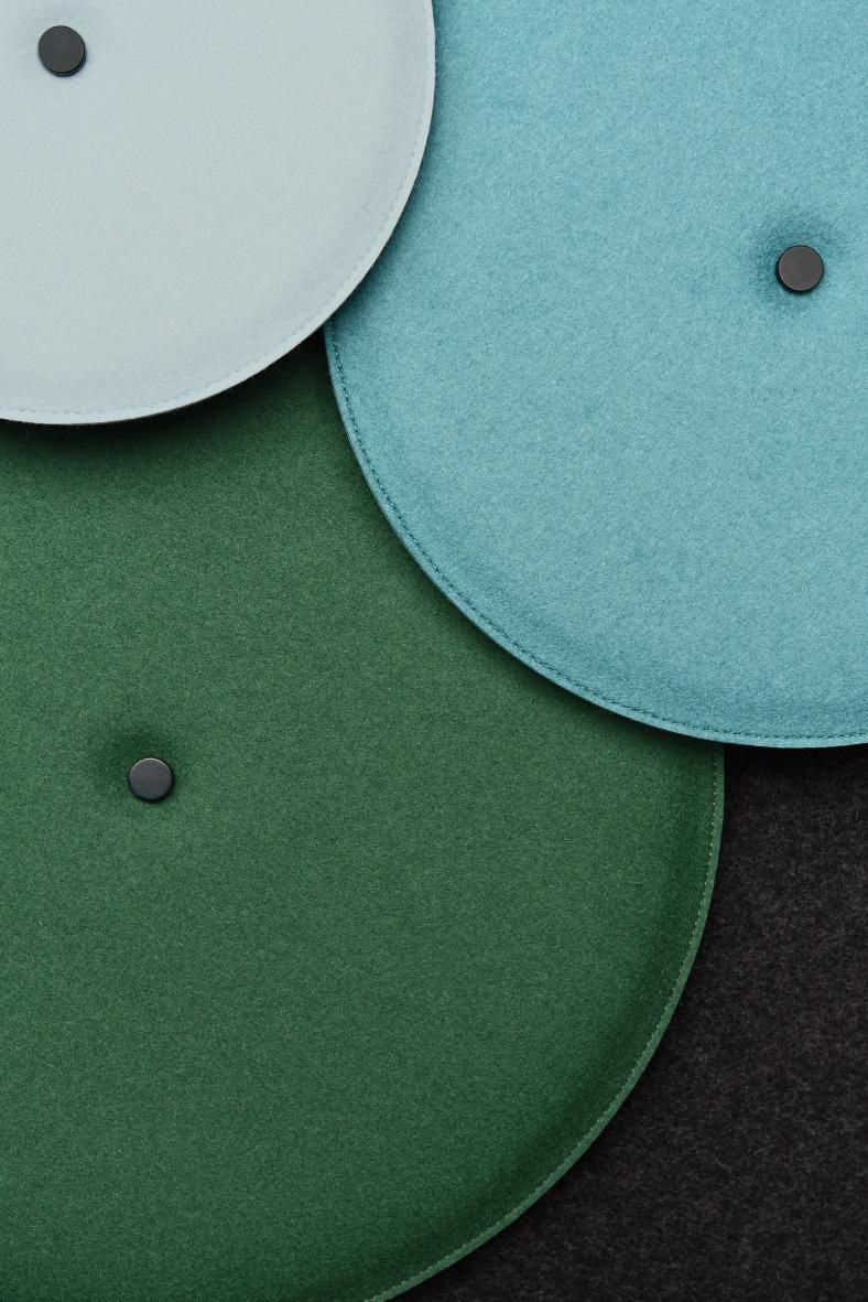 Detailaufnahme von runden Hey Sign Akustik Wandelementen in Grün-, Türkis- und Blautönen mit Knopf zur Schallabsorption.