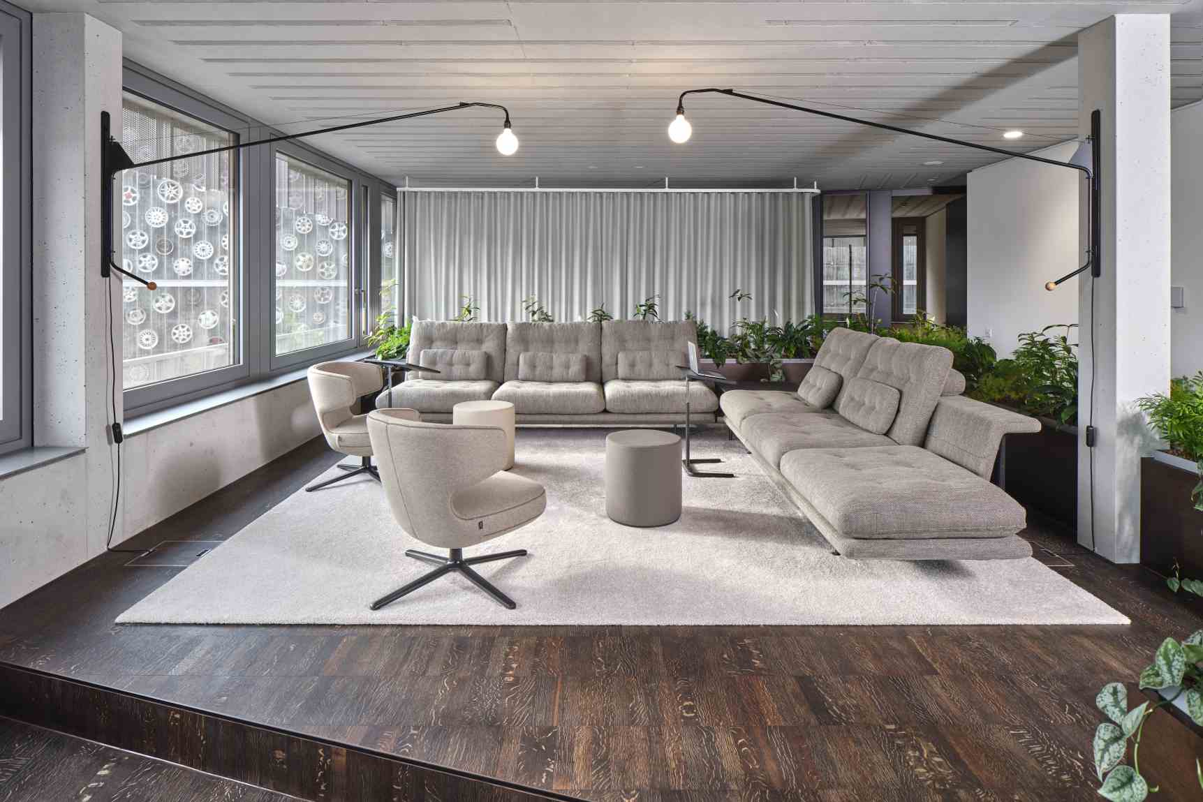 Grand Sofa 2,5-Sitzer von Vitra in hellem Stoffbezug, kombiniert mit Sesseln und Beistelltischen in modernem Wohnraum.