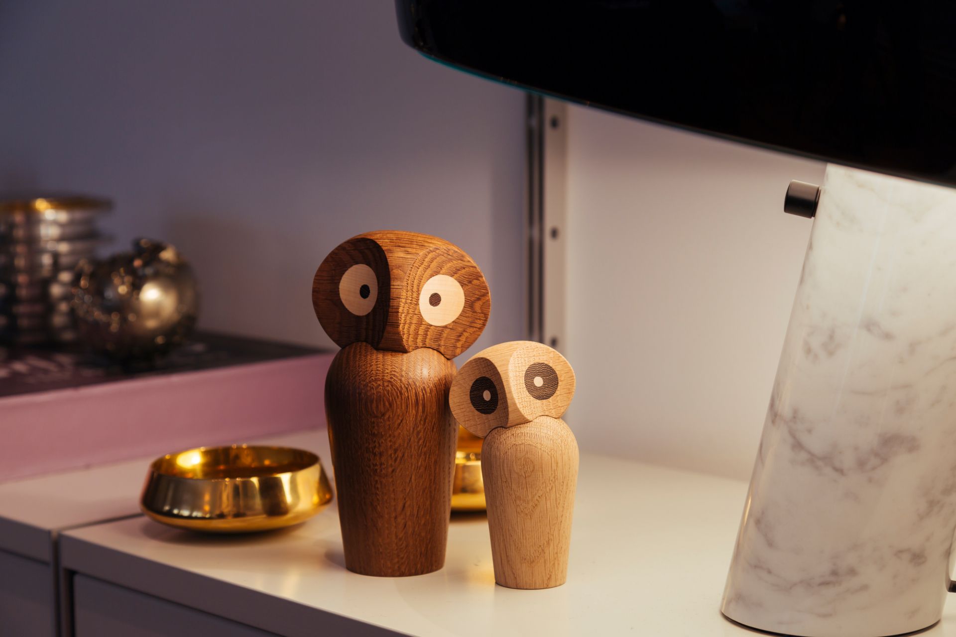 Zwei Architectmade Holzfiguren Eulen, unterschiedliche Größen, als Deko-Objekt auf einem Regal.