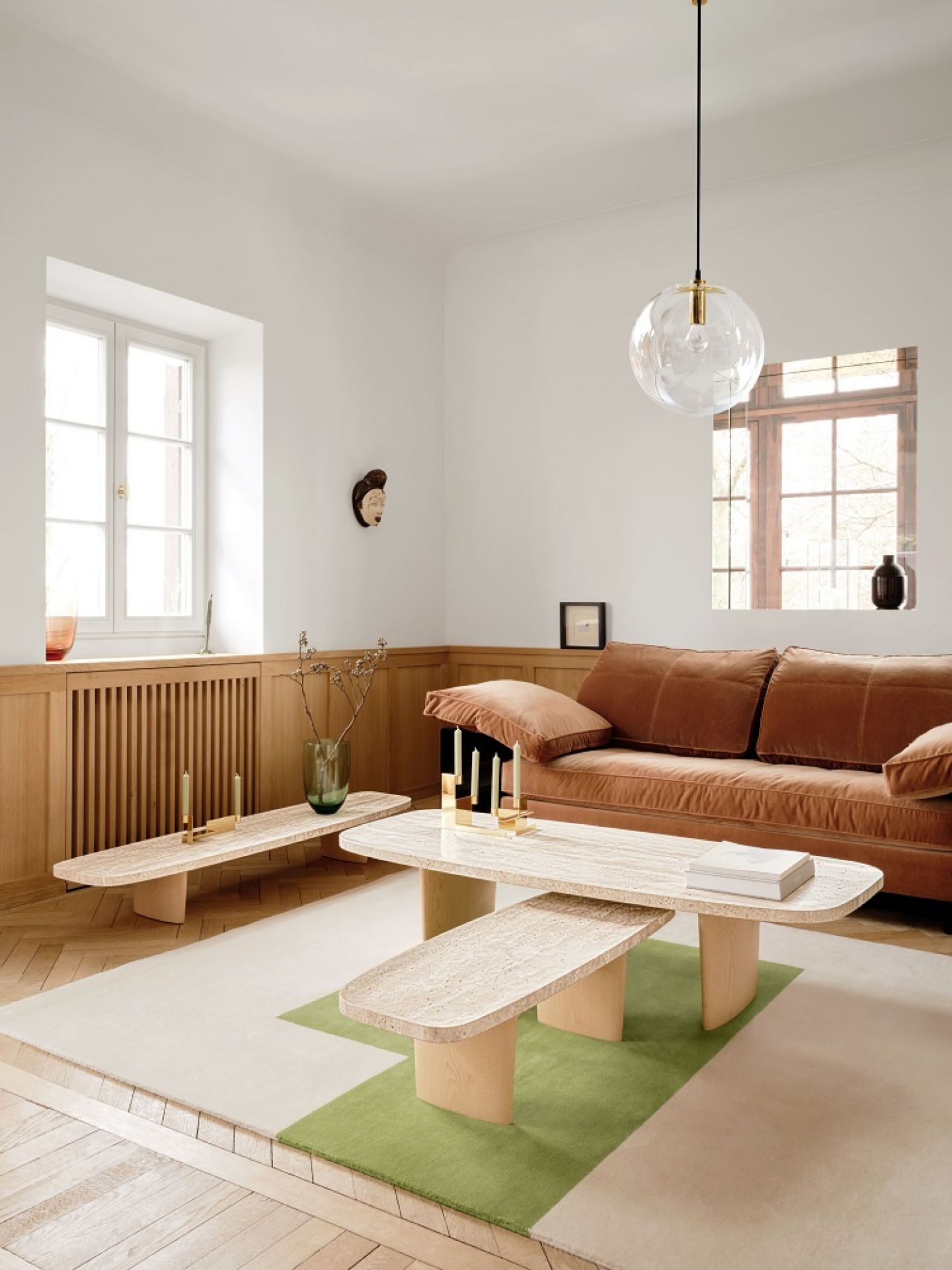 Wohnzimmer mit Classicon Beistelltisch Matéria, Couch, Teppich und Lampe. Moderner Beistelltisch aus Travertin.