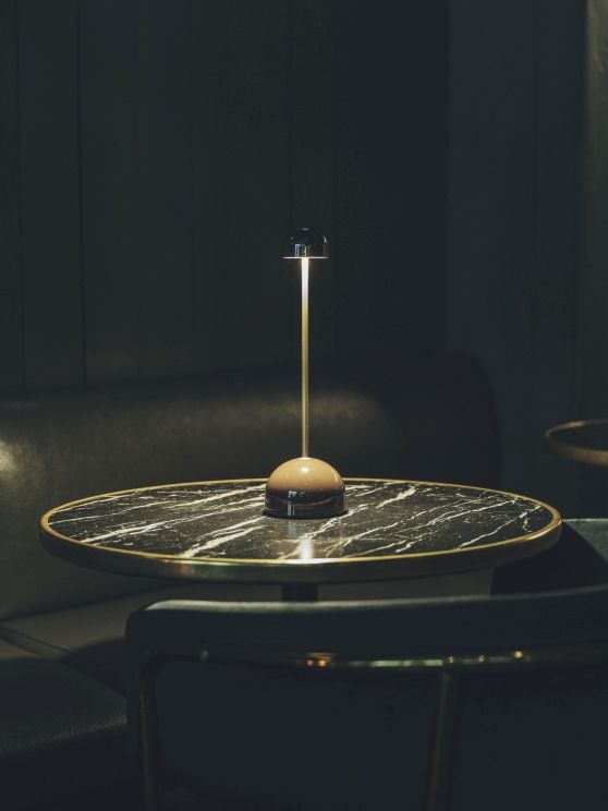 Sips Akkuleuchte von Marset in Weiß/Silber auf einem Marmortisch, stimmungsvolle Tischleuchte.