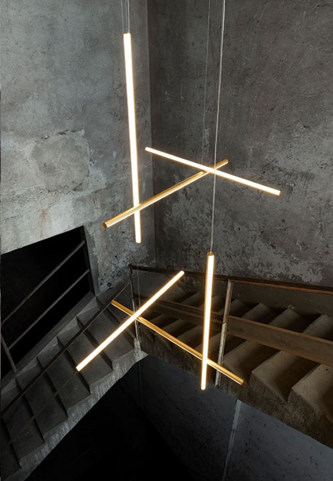 Flos Coordinates S1 LED Pendelleuchte mit goldenen, linearen Leuchtelementen über einer Treppe.