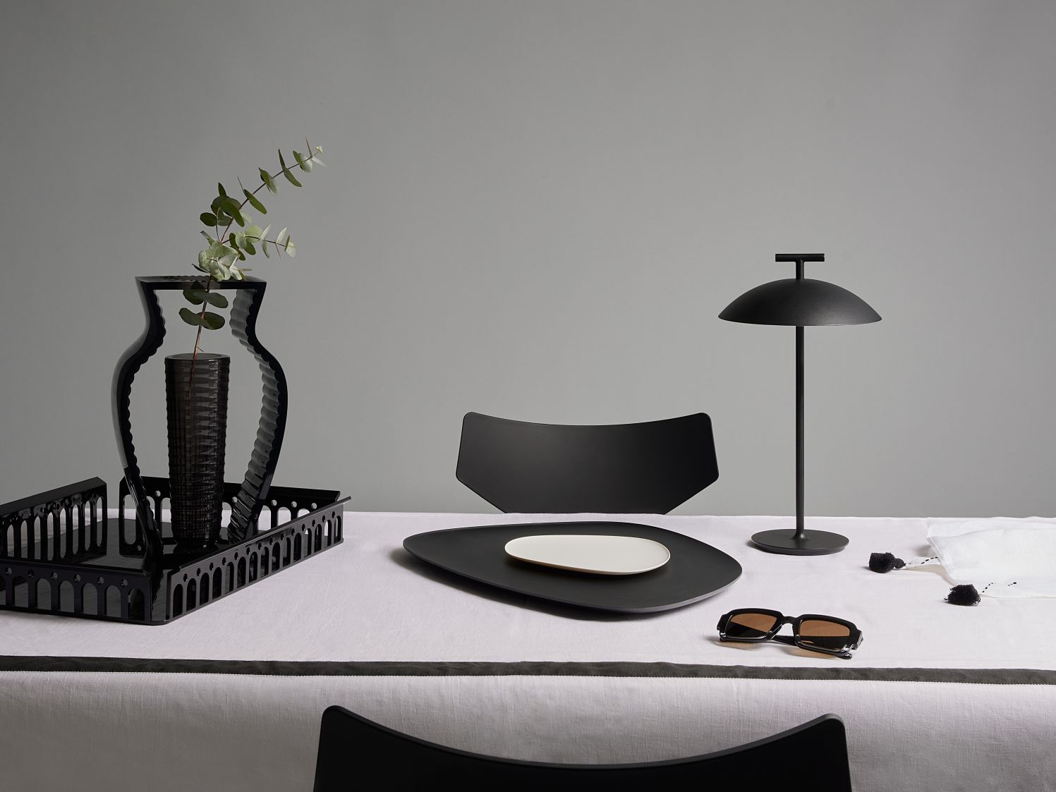 Nahaufnahme der Mini Geen-A Tischlampe von Kartell in Ziegelrot, batteriebetrieben, auf gedecktem Tisch.