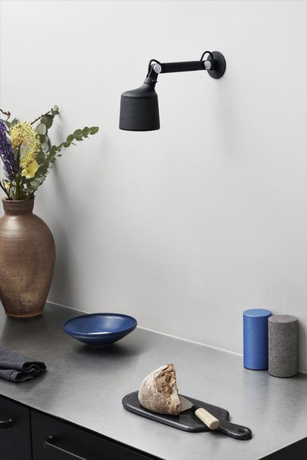 Schwarze Vipp Wandlampe klein über Küchentheke mit Brot, Schale und Gewürzdosen, modernes Küchendesign.