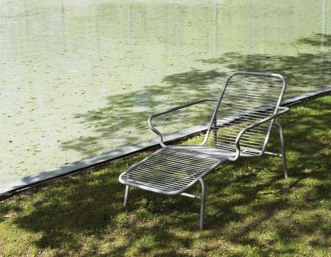Graue Vig Chaise Longue von Normann Copenhagen im Freien auf Rasen, neben einem Teich.