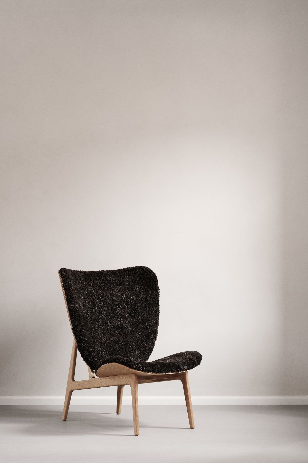 NORR11 Elephant Lounge Chair Sessel mit dunklem Fellbezug und hellem Holzgestell. Design Möbel.