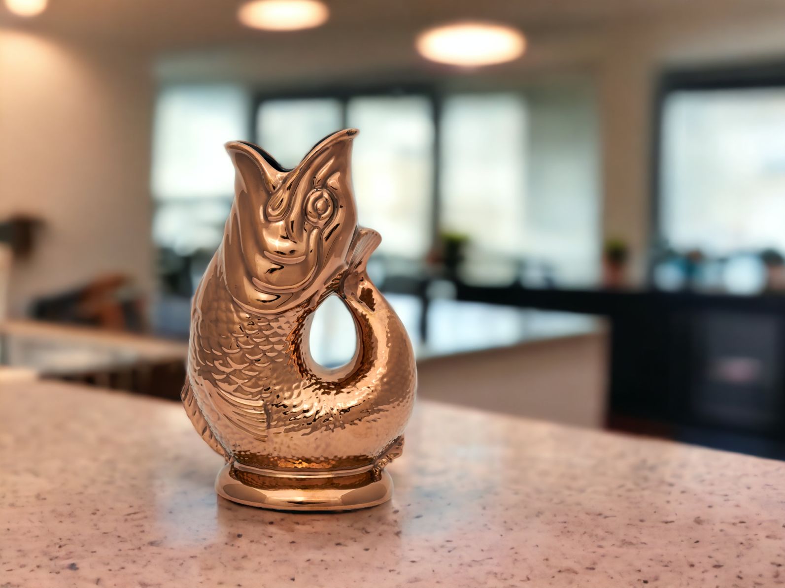 Nahaufnahme der kupferfarbenen Gluckigluck Fischkaraffe auf einer Küchentheke. Dekorative Wasserkaraffe im Fischdesign.