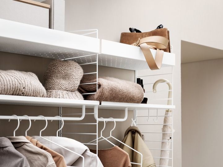 Detailaufnahme des Flur KONFIGURATIONEN String Regalsystems mit Kleidung, Tasche und Accessoires.