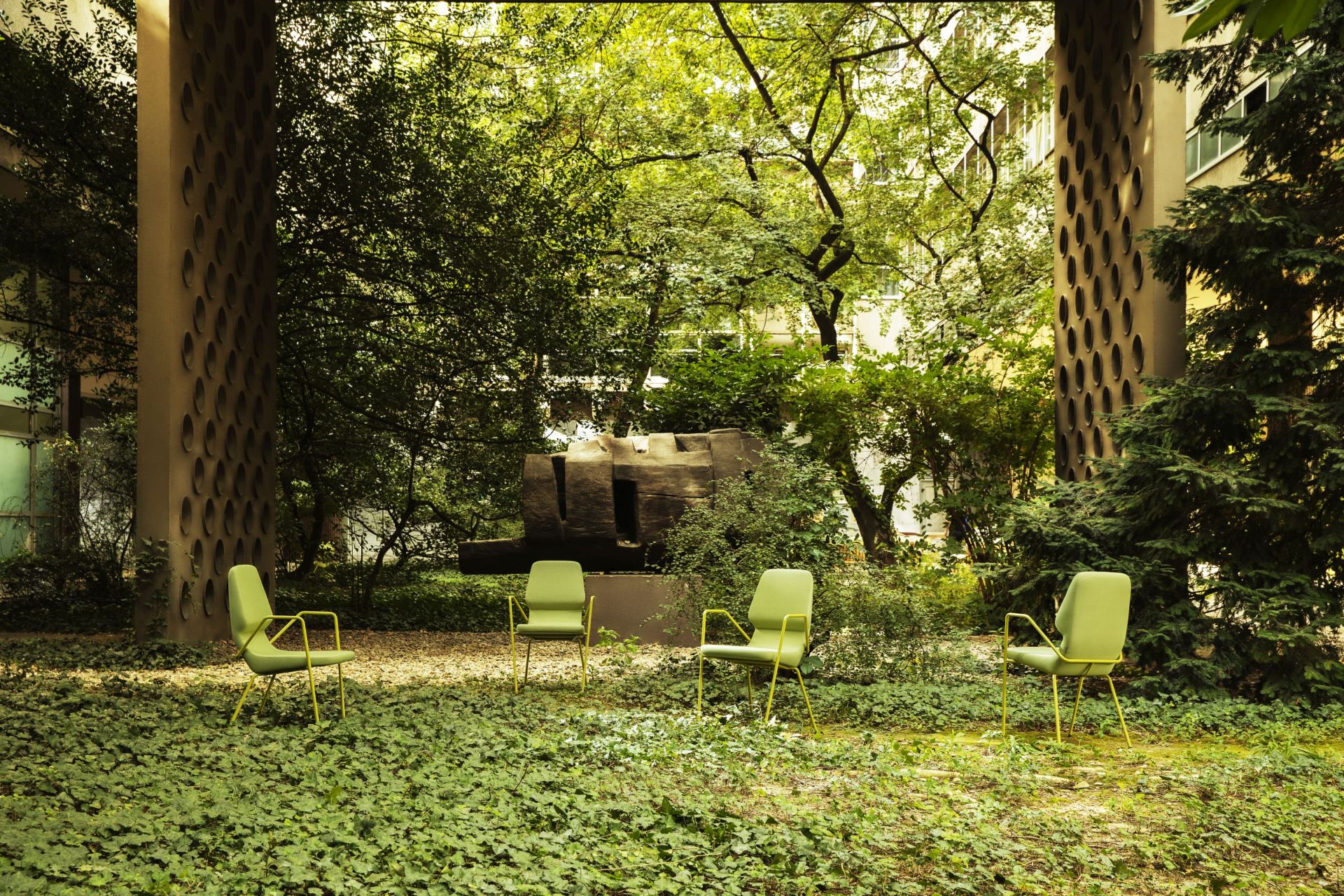 Vier grüne Prostoria Oblique Sessel im Freien, umgeben von üppigem Grün. Outdoor Sessel für Garten und Terrasse.