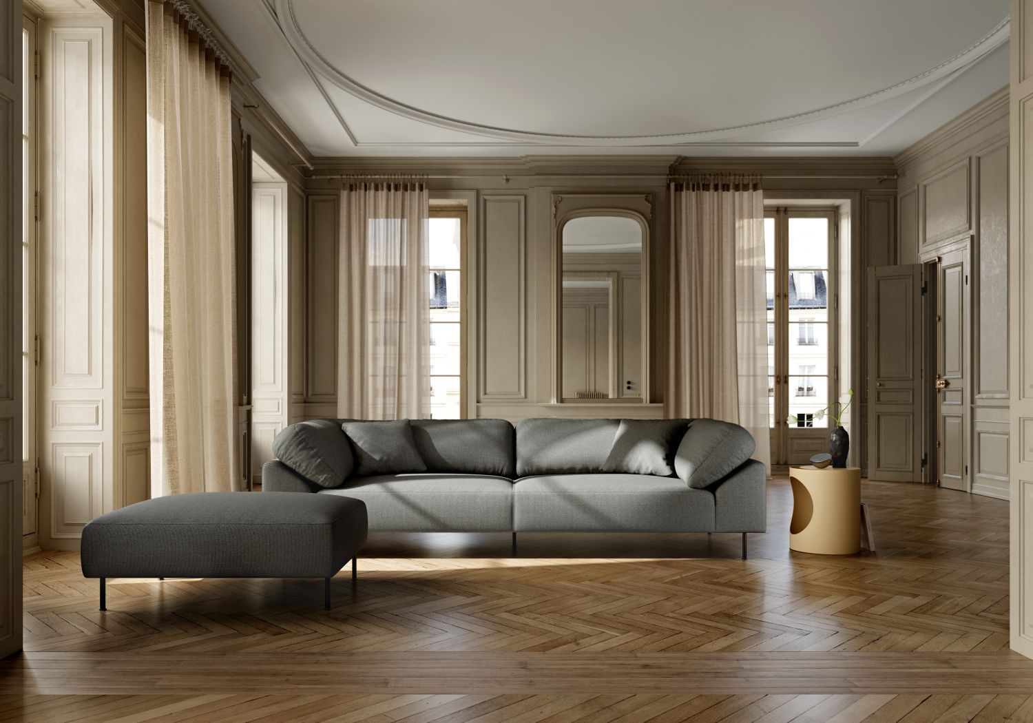 Grauer Collar Ottoman von Woud vor Sofa in elegantem Wohnzimmer mit Parkettboden.