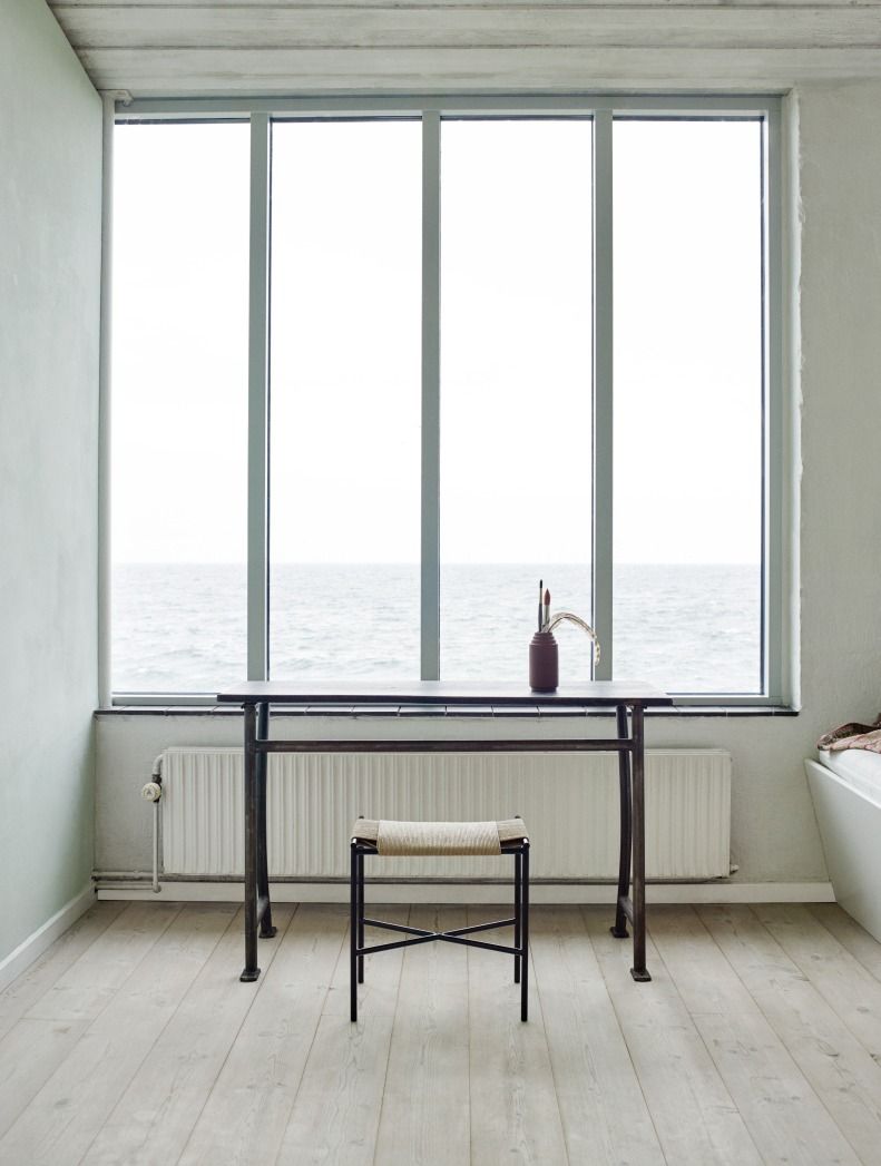 Vent Hocker von Skagerak by Fritz Hansen vor Fenster mit Meerblick, minimalistisches Design.