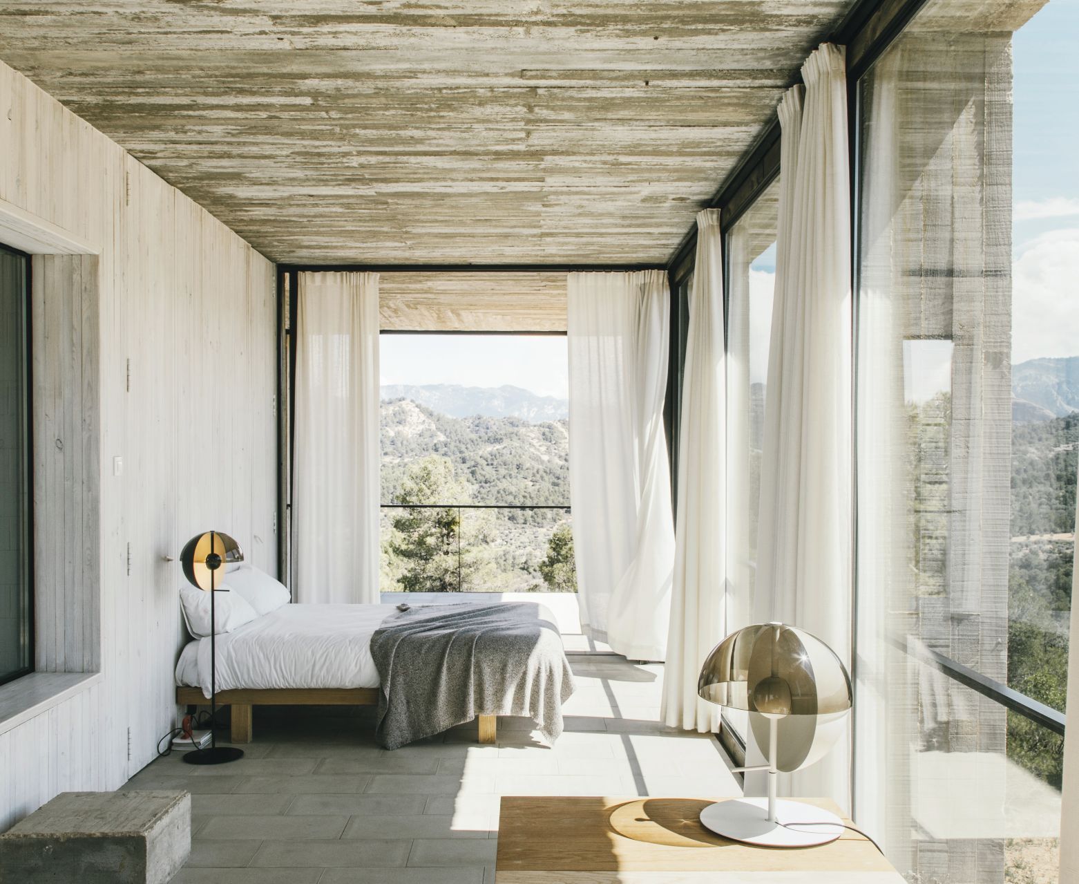 Schlafzimmer mit Bett und schwarzer Theia Tischleuchte von Marset, modernes Design mit indirektem Licht.