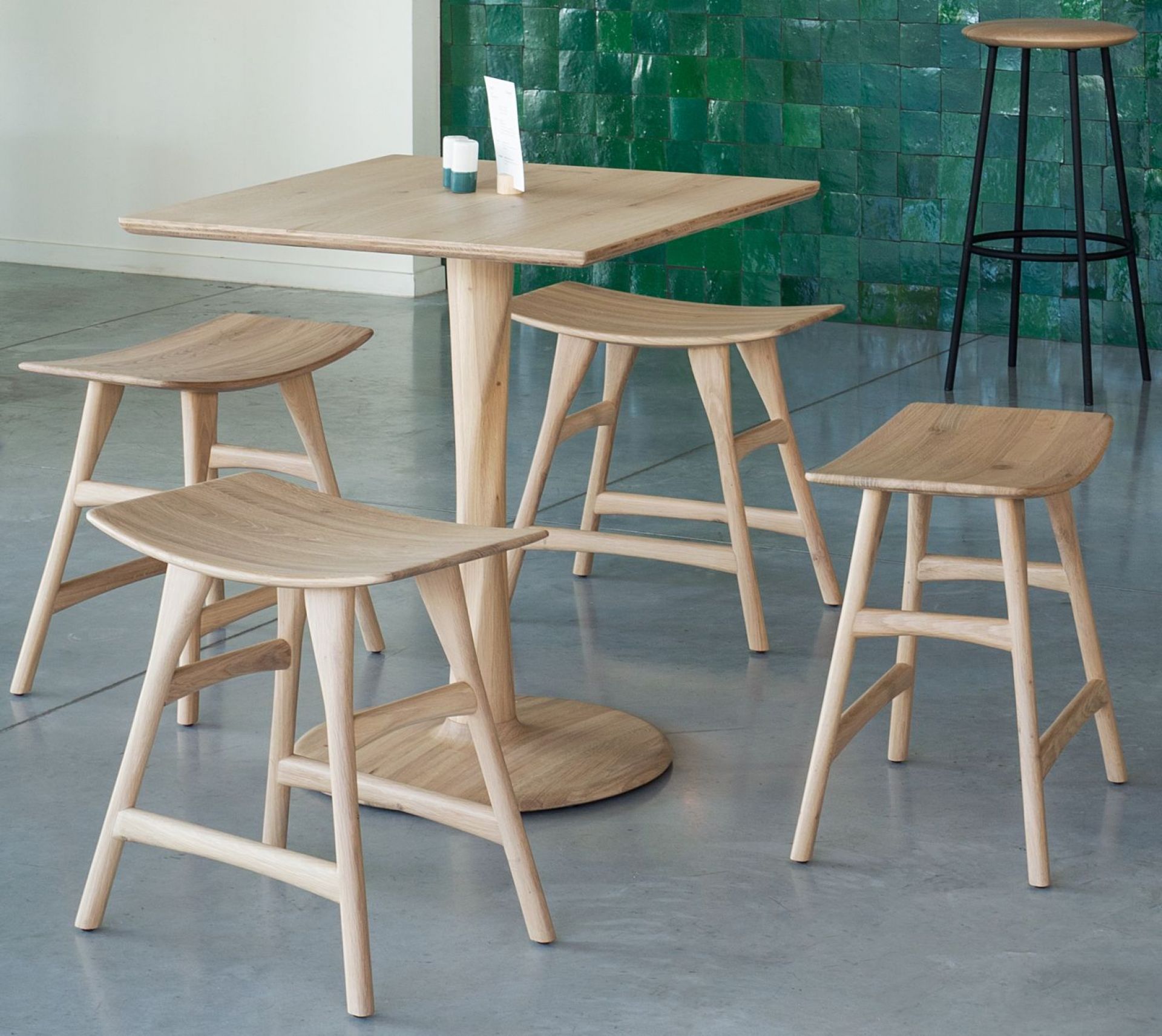 Ethnicraft Osso Stuhl aus Eiche mit passendem Tisch und Barhocker im Hintergrund.