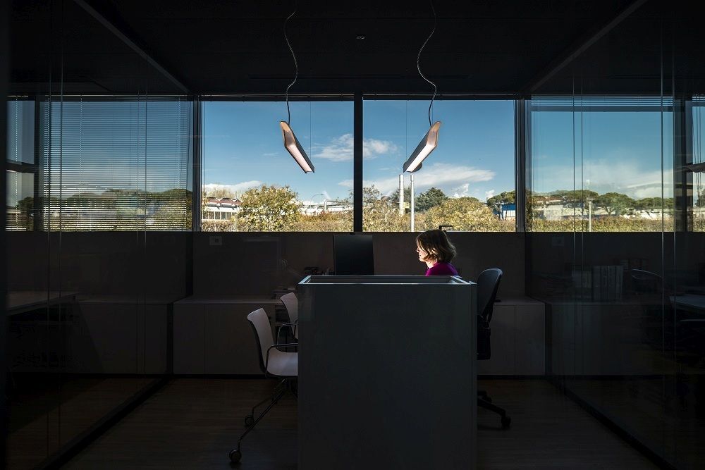 Moderne Troag LED Hängeleuchte von Foscarini über einem Schreibtisch in einem Büro mit großer Fensterfront.