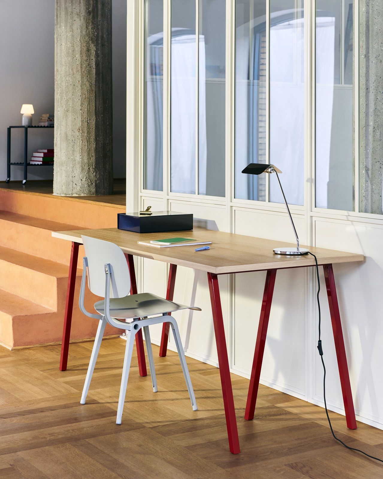 Hay Loop Stand Table mit rotem Gestell und Schreibtischstuhl in einem modernen Büro.
