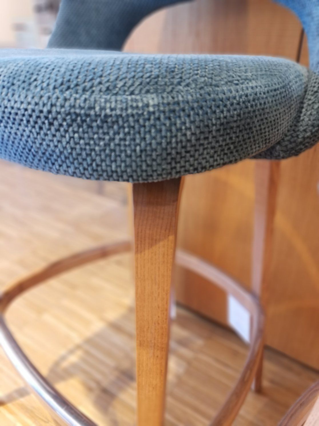 Detailaufnahme: Saarinen Barhocker mit blauem Stoffbezug und Holzgestell, ein Ausstellungsstück.
