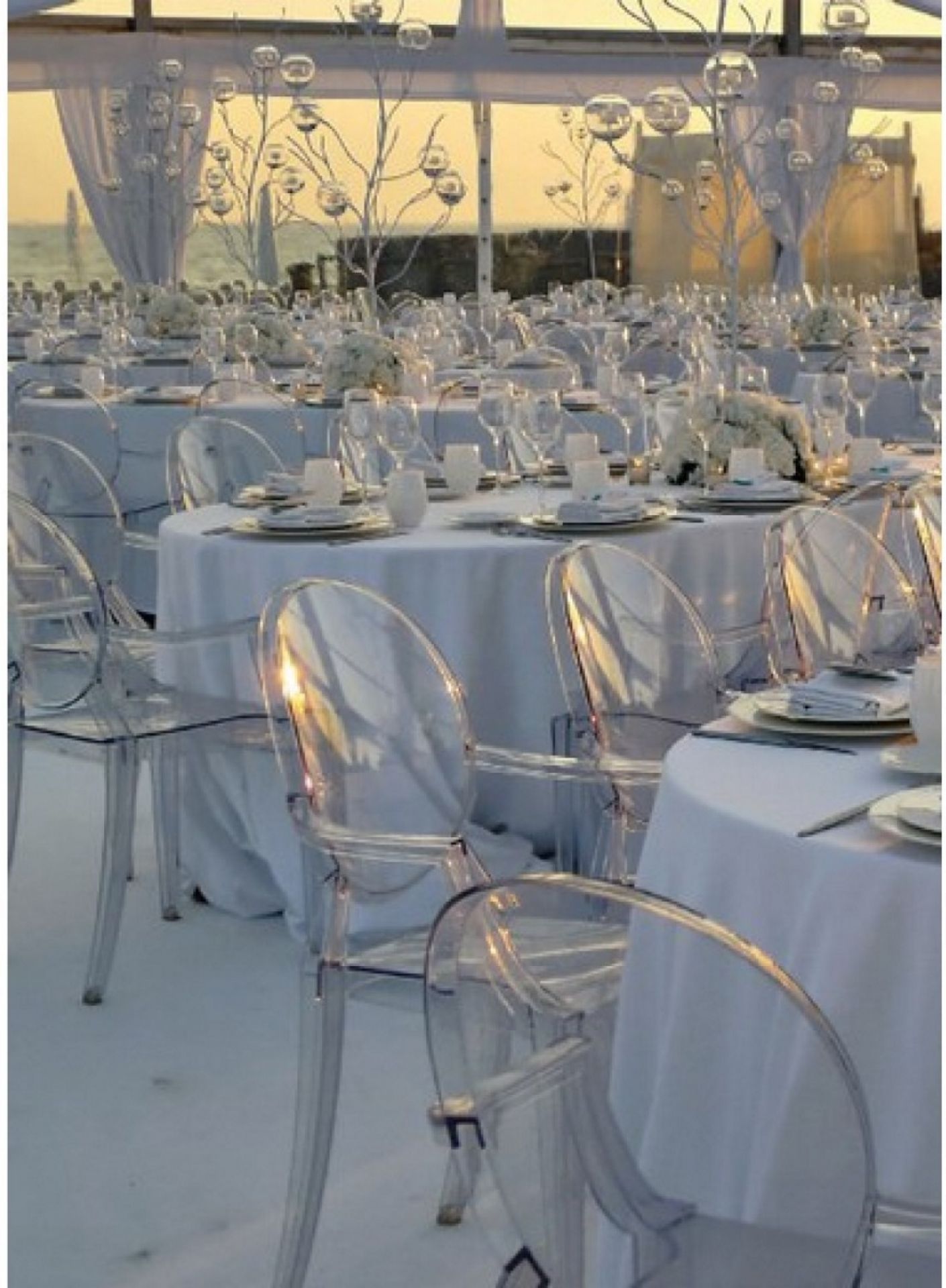 Festlich gedeckte Tische mit glasklaren Louis Ghost Armlehnstühlen von Kartell für elegante Events.