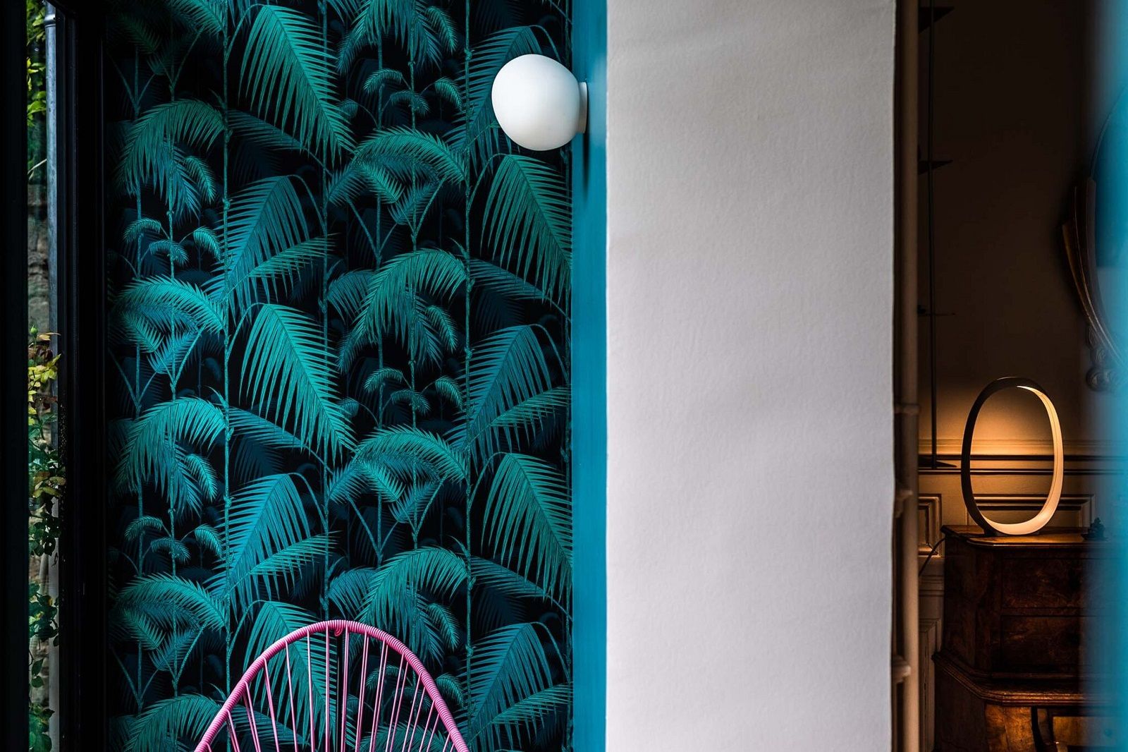 Weiße Gregg Wandleuchte von Foscarini an Wand mit tropischem Palmenmuster. Moderne Innenraumbeleuchtung.